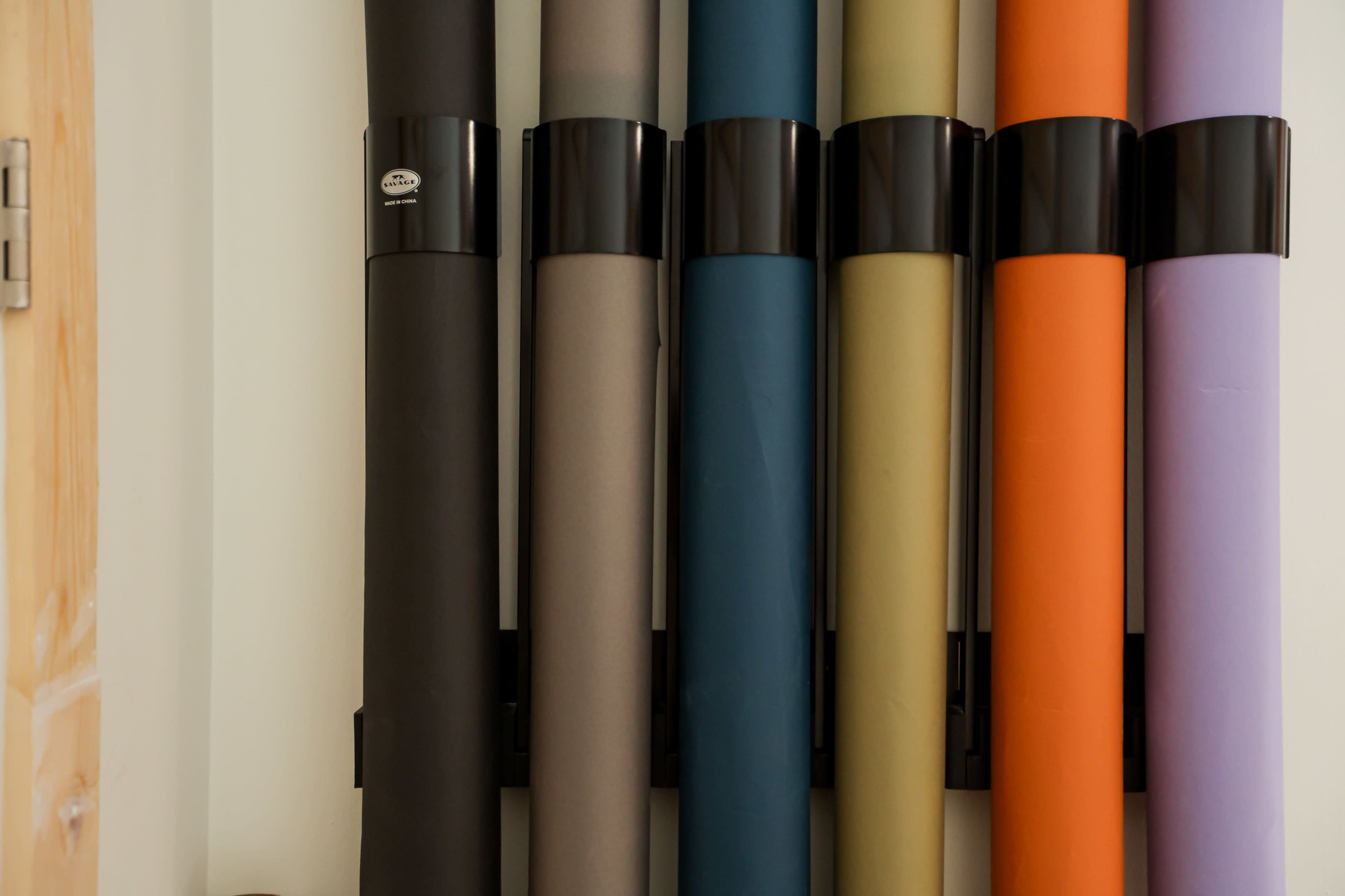 The image shows a collection of rolls of colored backdrops arranged vertically on a wall.