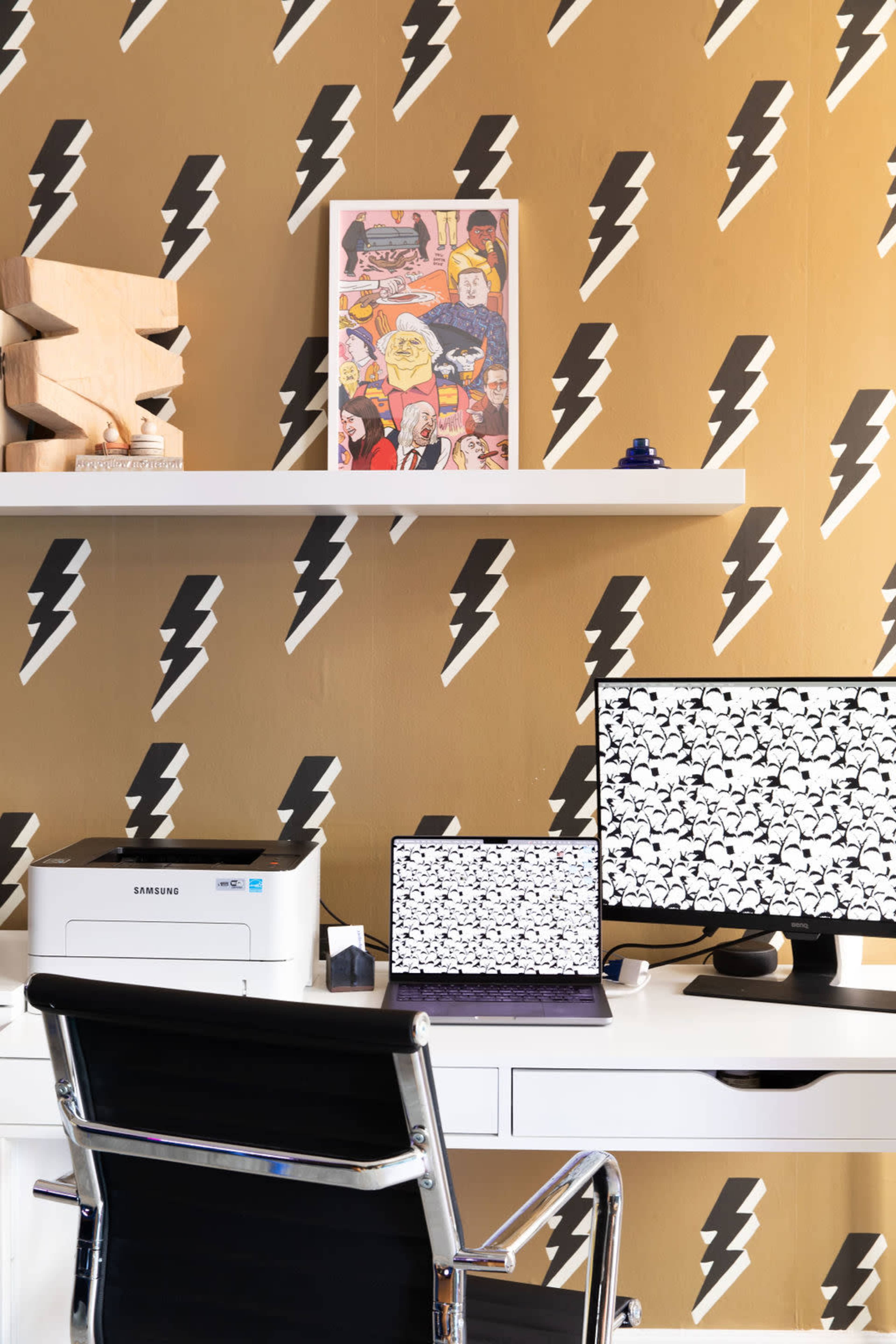 The image shows a modern workspace featuring a desk with a computer, a printer, and decorative elements against a lightning bolt patterned wallpaper.