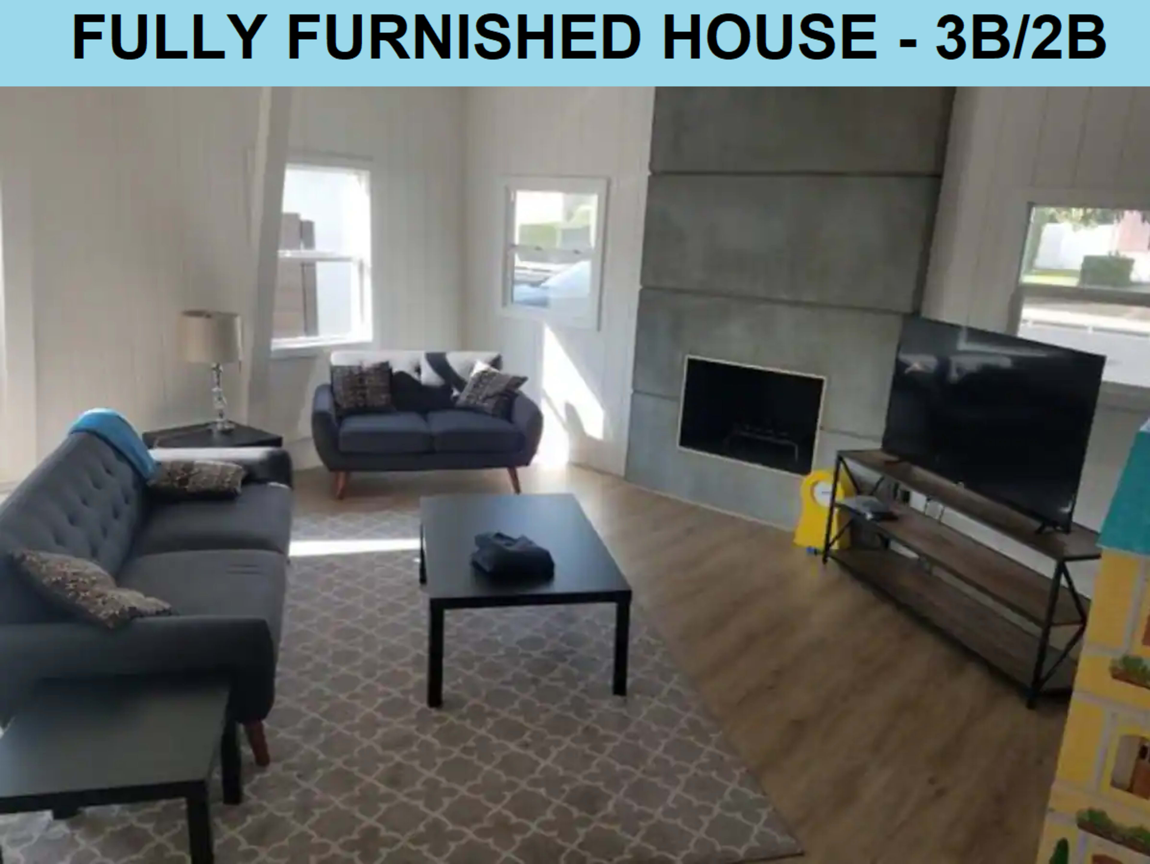 A living room features two sofas, a coffee table, a fireplace, and a television on a stand.