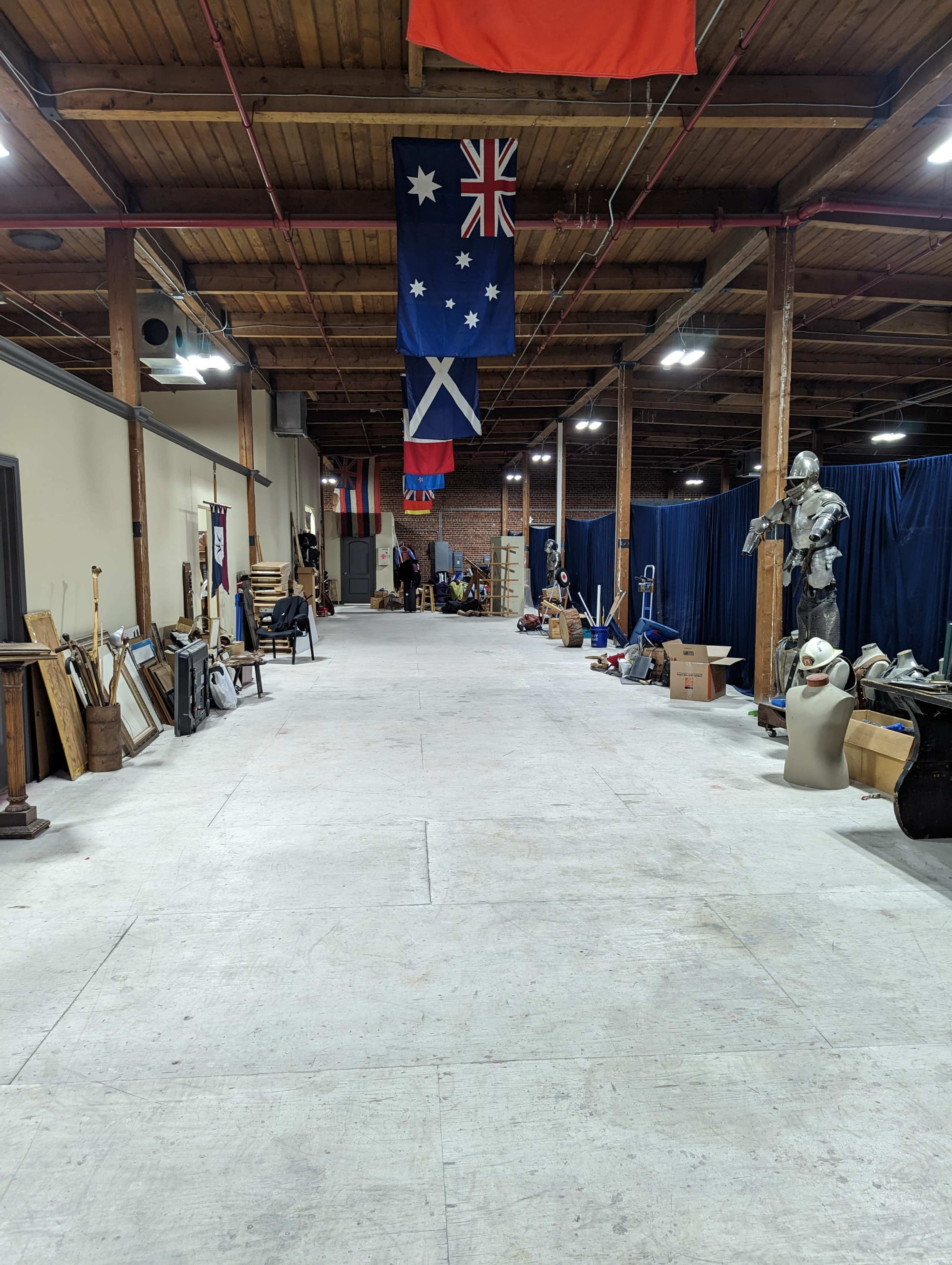 A long, empty hallway in a warehouse with various items and flags hanging from the ceiling.