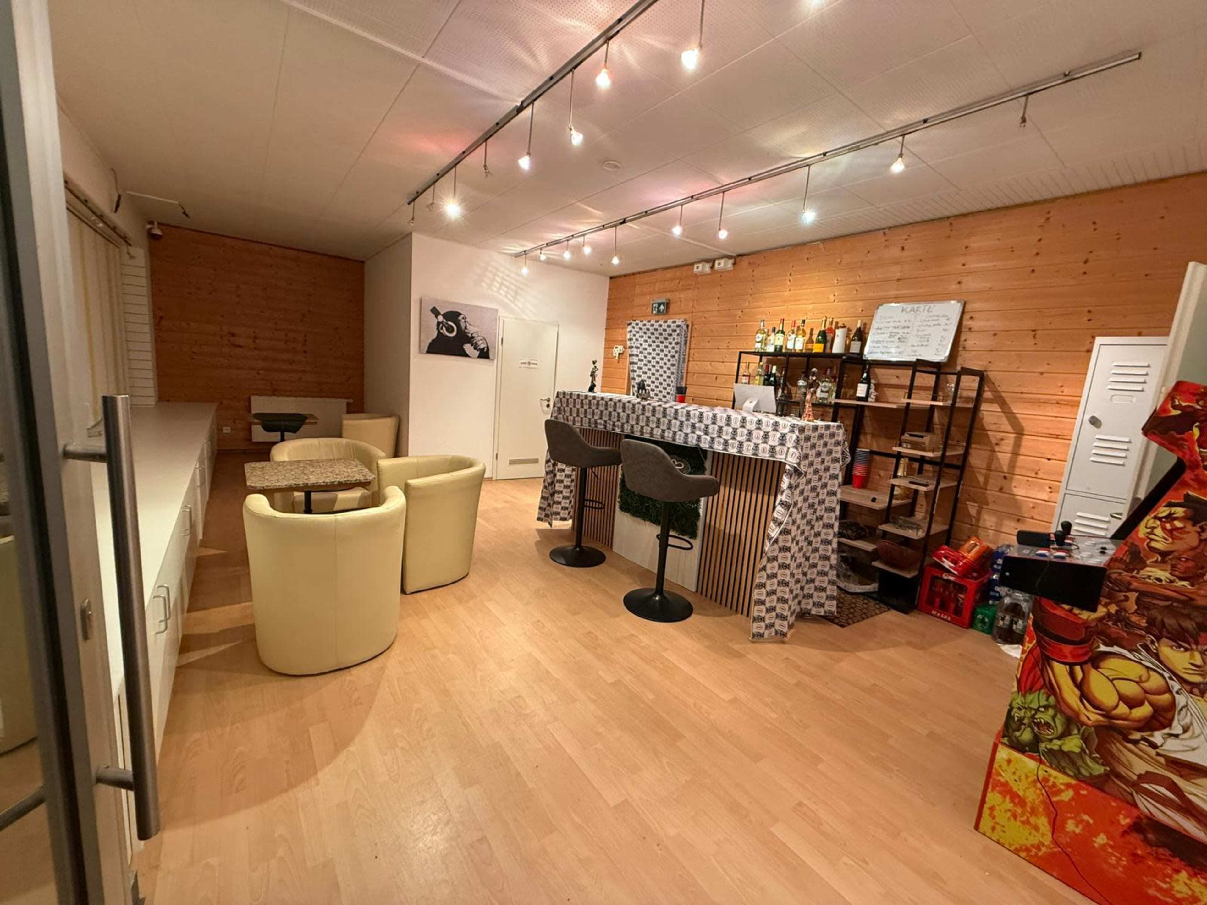 The image shows a modern interior space with a bar area, seating arrangements, and wooden walls.