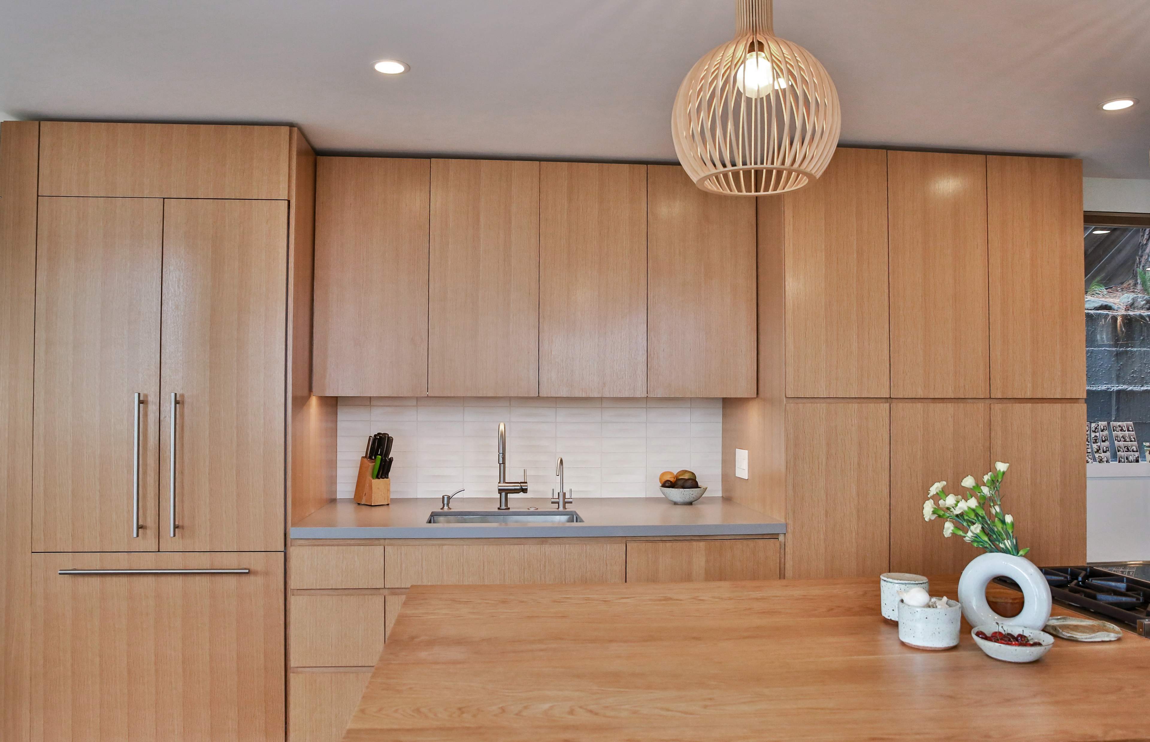 The kitchen features light wood cabinetry and a modern island with a minimalist design.