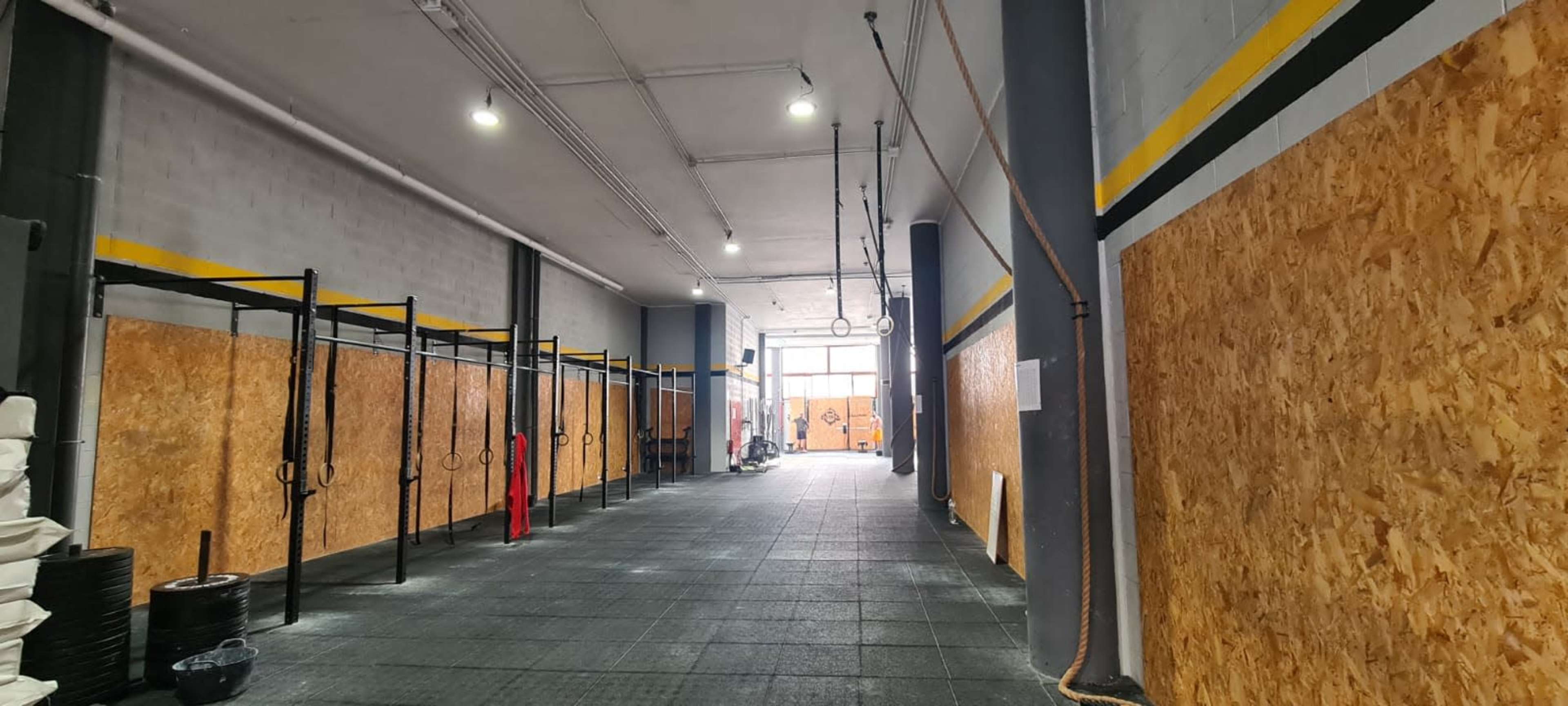 The interior of a gym with wooden paneling, workout stations along the walls, and various equipment on the floor.