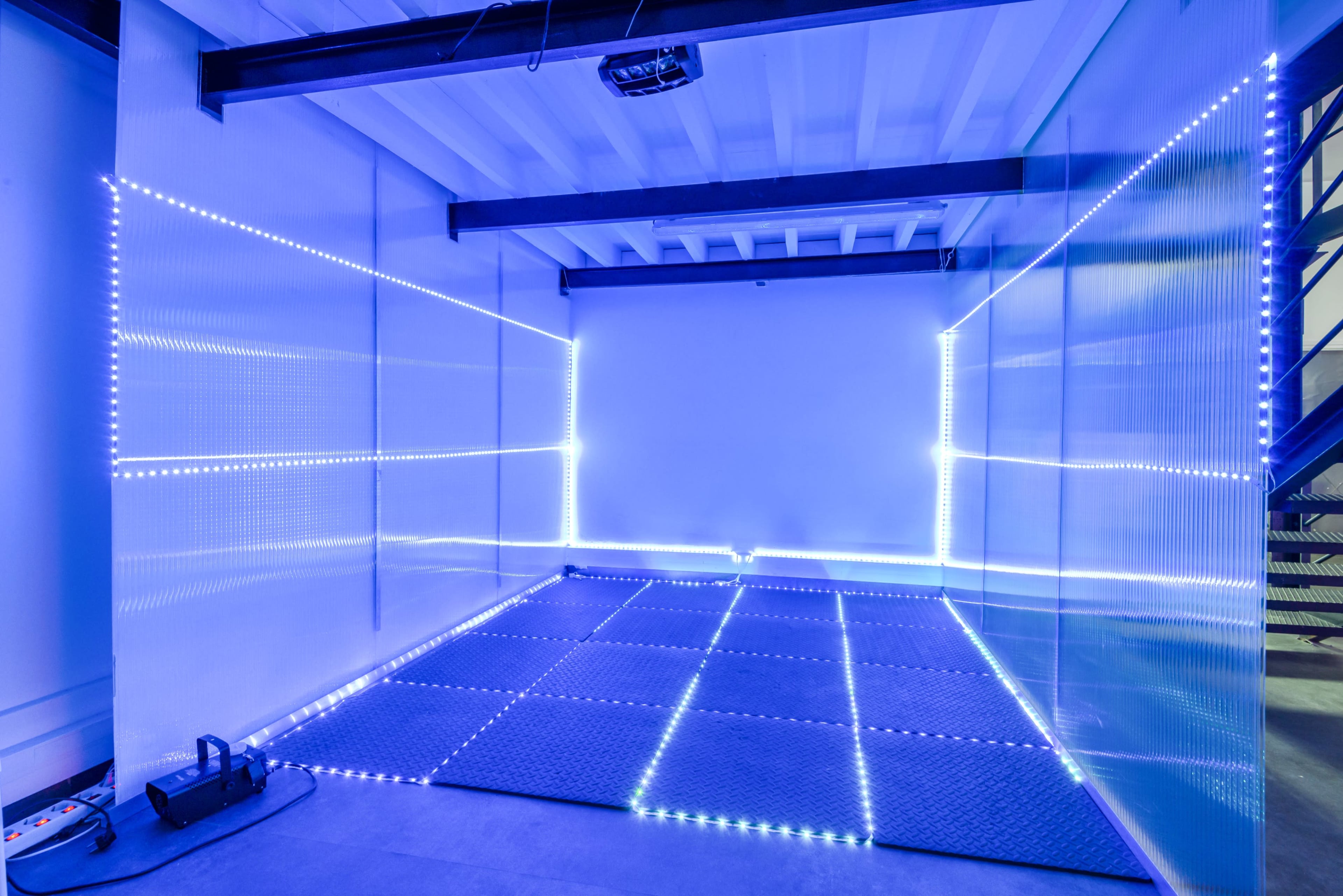 A room with a smooth floor and walls lined with blue LED lights, creating a minimalist and modern space.
