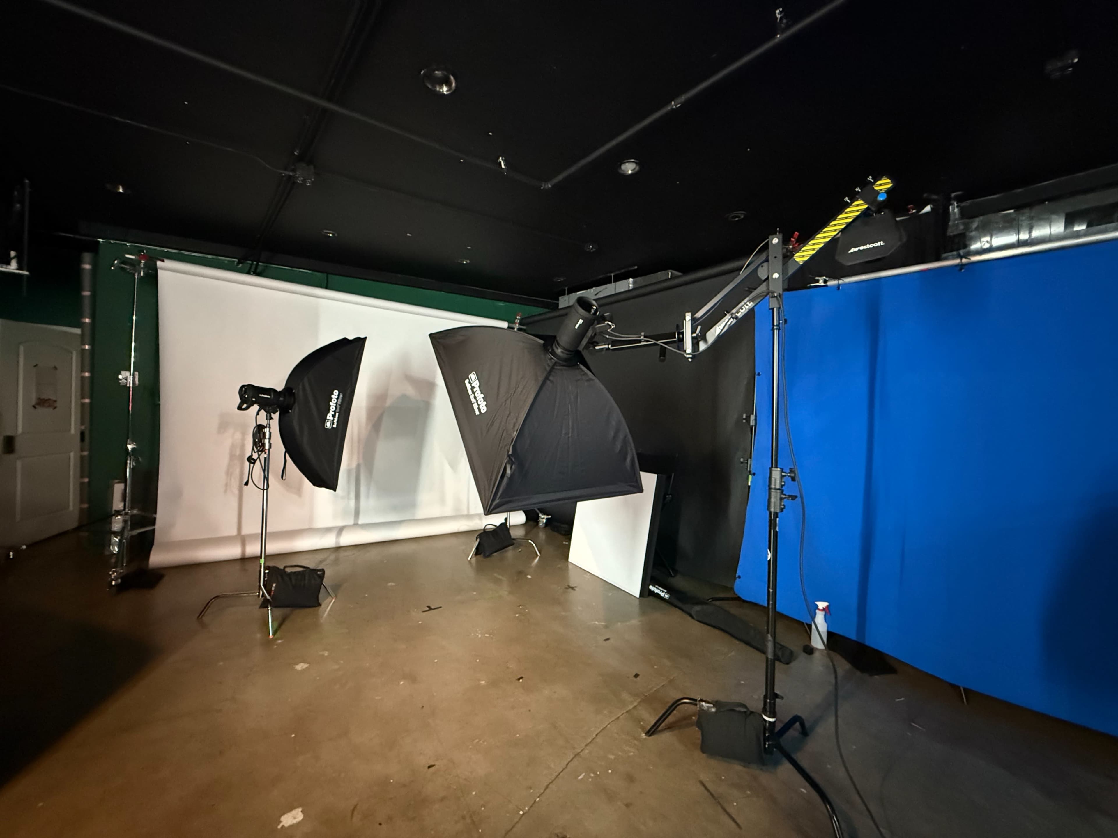 The image shows a photography studio setup with multiple lighting equipment, backdrops, and stands positioned in a dimly lit space.