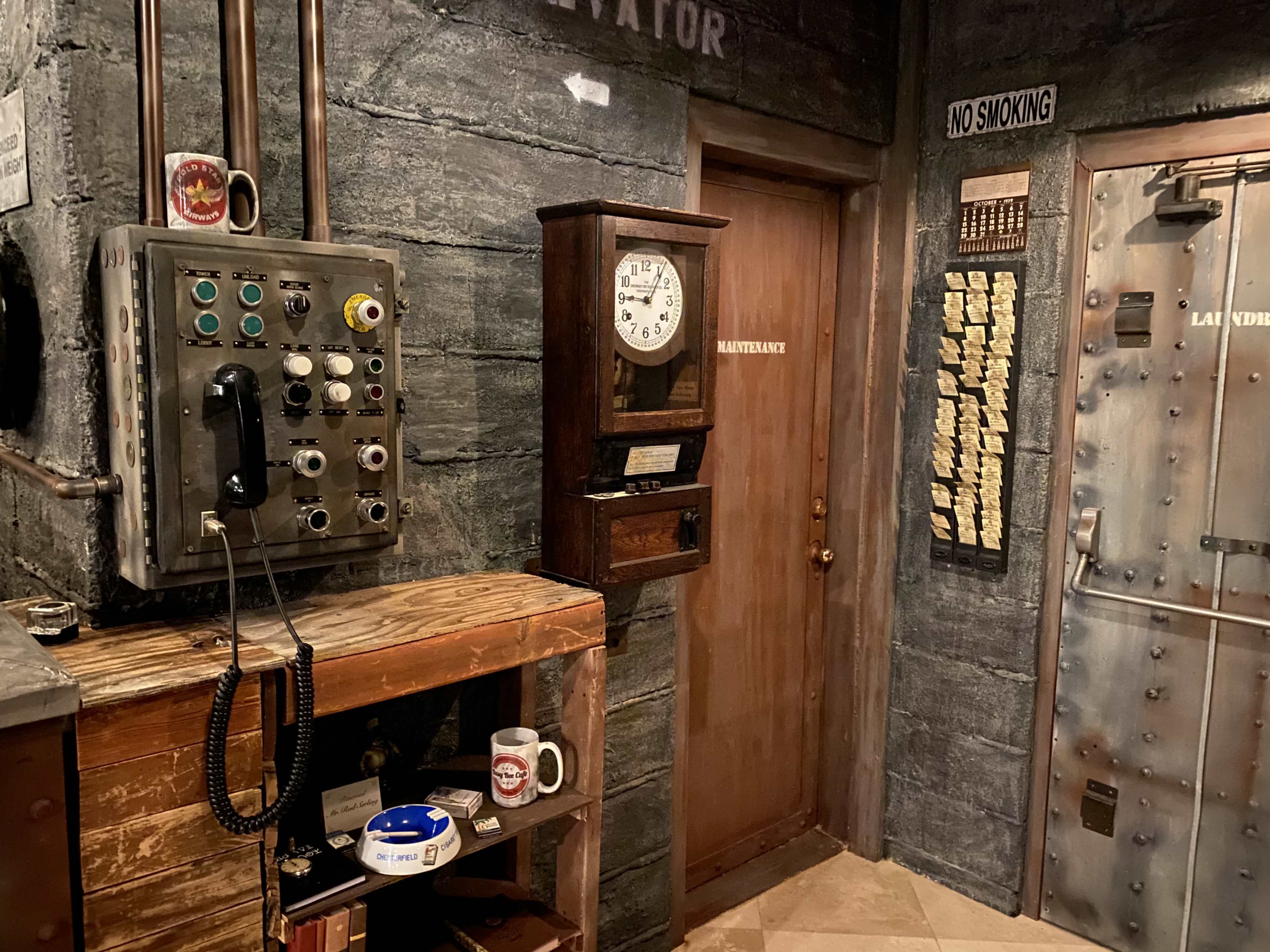 The image shows a dimly lit room with a vintage clock, an old-fashioned telephone on a wooden table, and a metal door labeled "LAUNDRY."