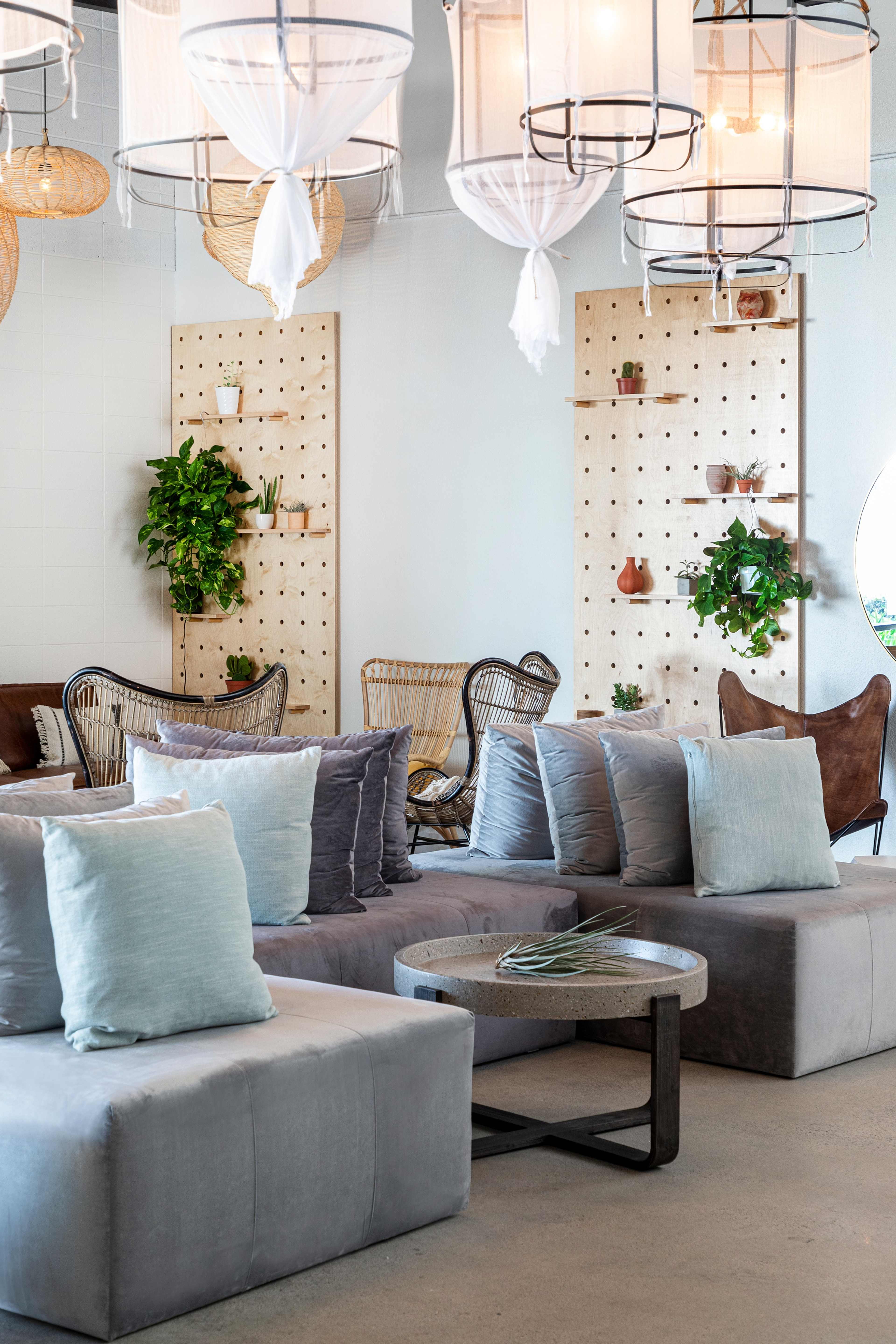 A modern lounge area with soft seating, decorative plants on wooden panels, and stylish light fixtures.