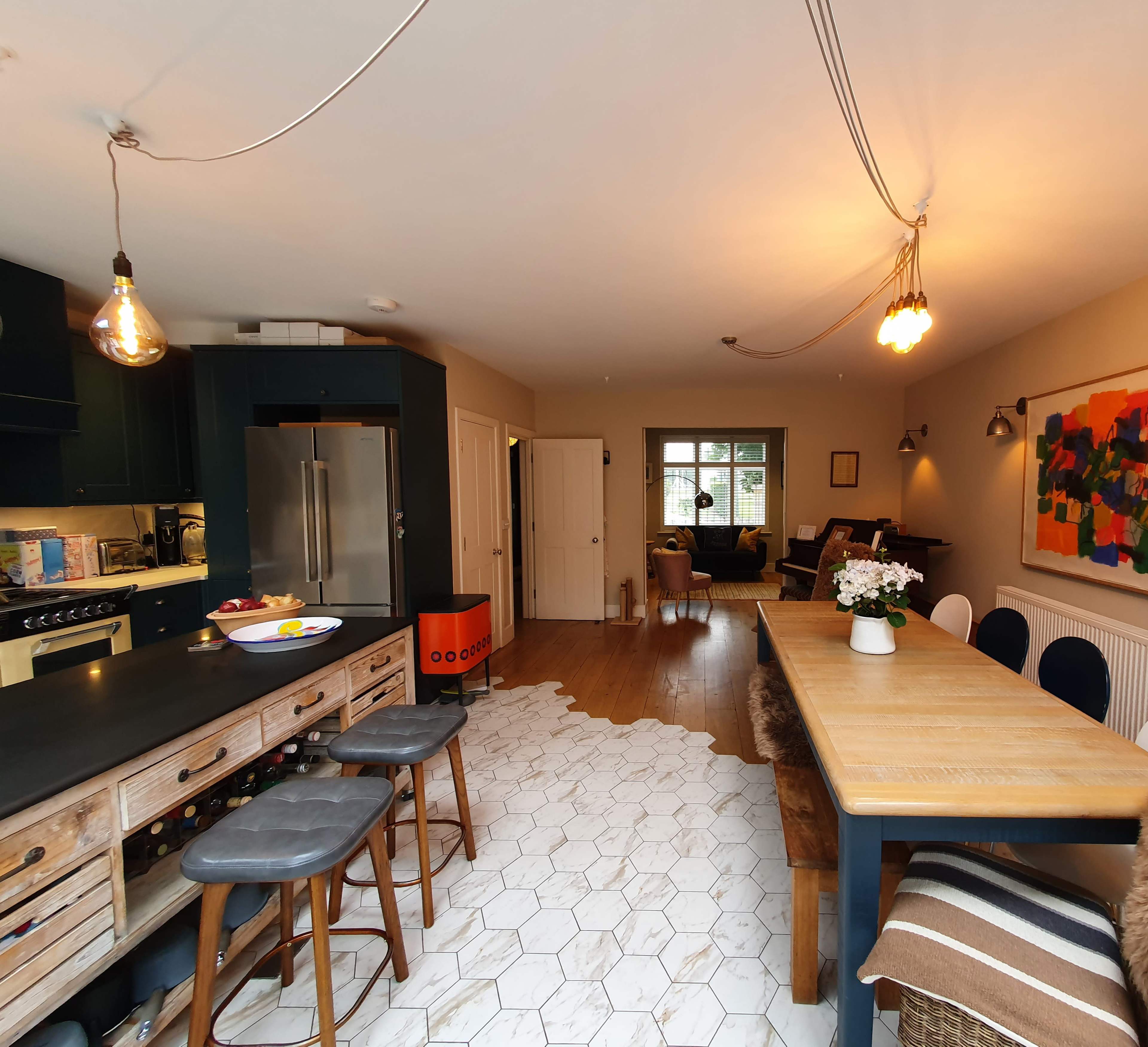 A modern kitchen and dining area with wooden furniture, a large island, and a vibrant artwork on the wall.