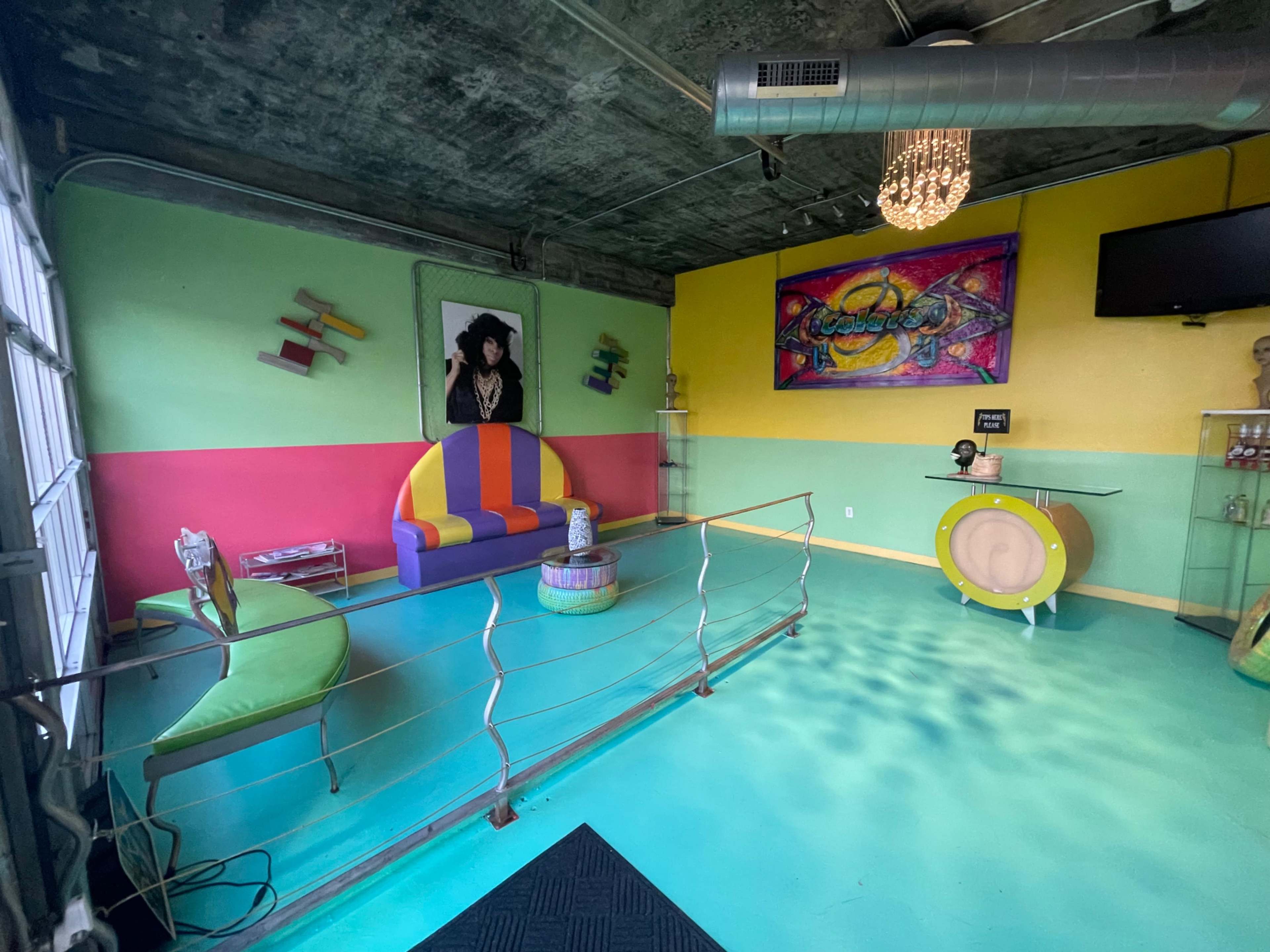 A colorful lounge space featuring a multi-colored seating area, vibrant wall art, and a polished turquoise floor.