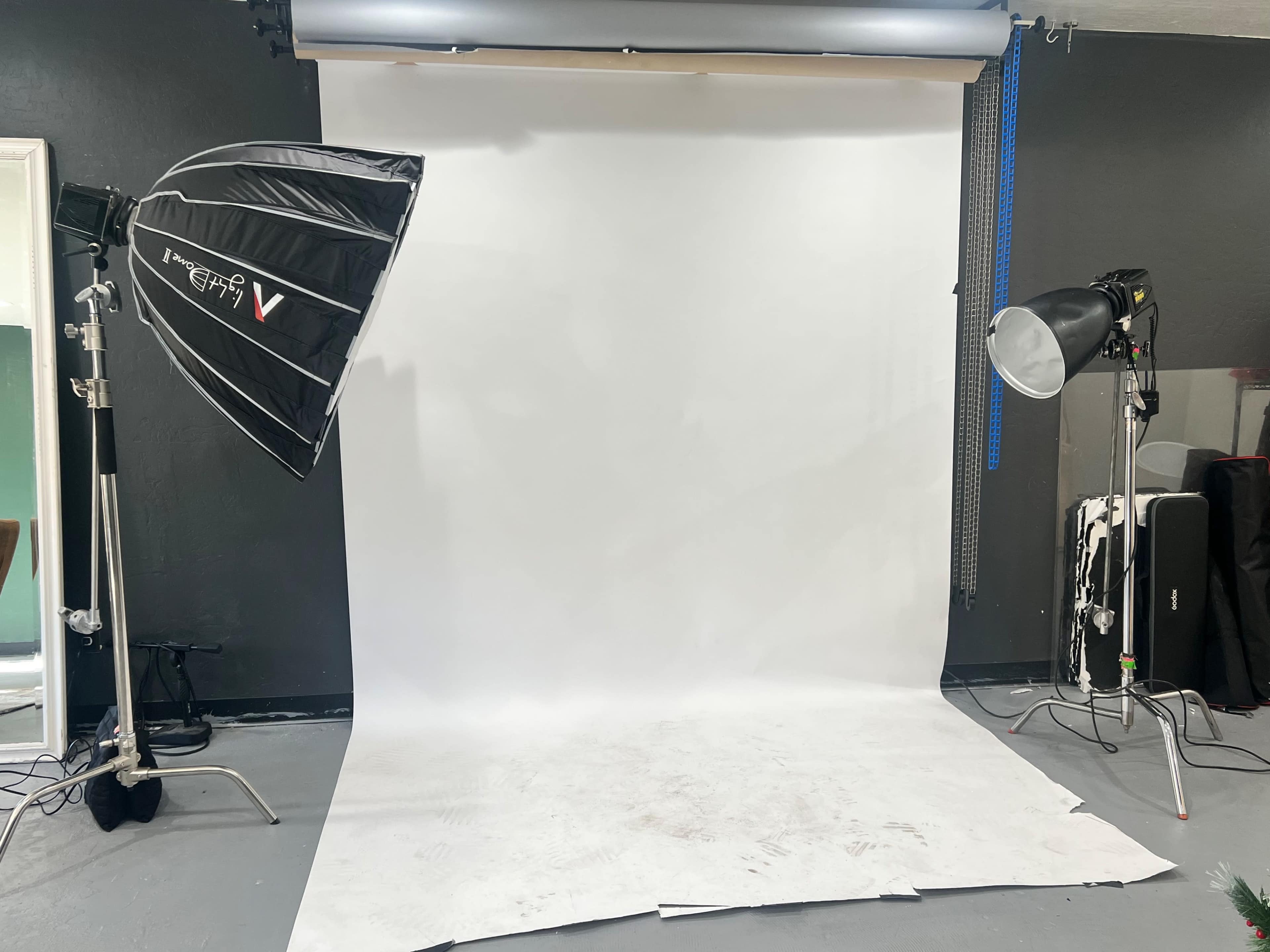A photography studio setup with a large white backdrop and two light sources positioned on either side.