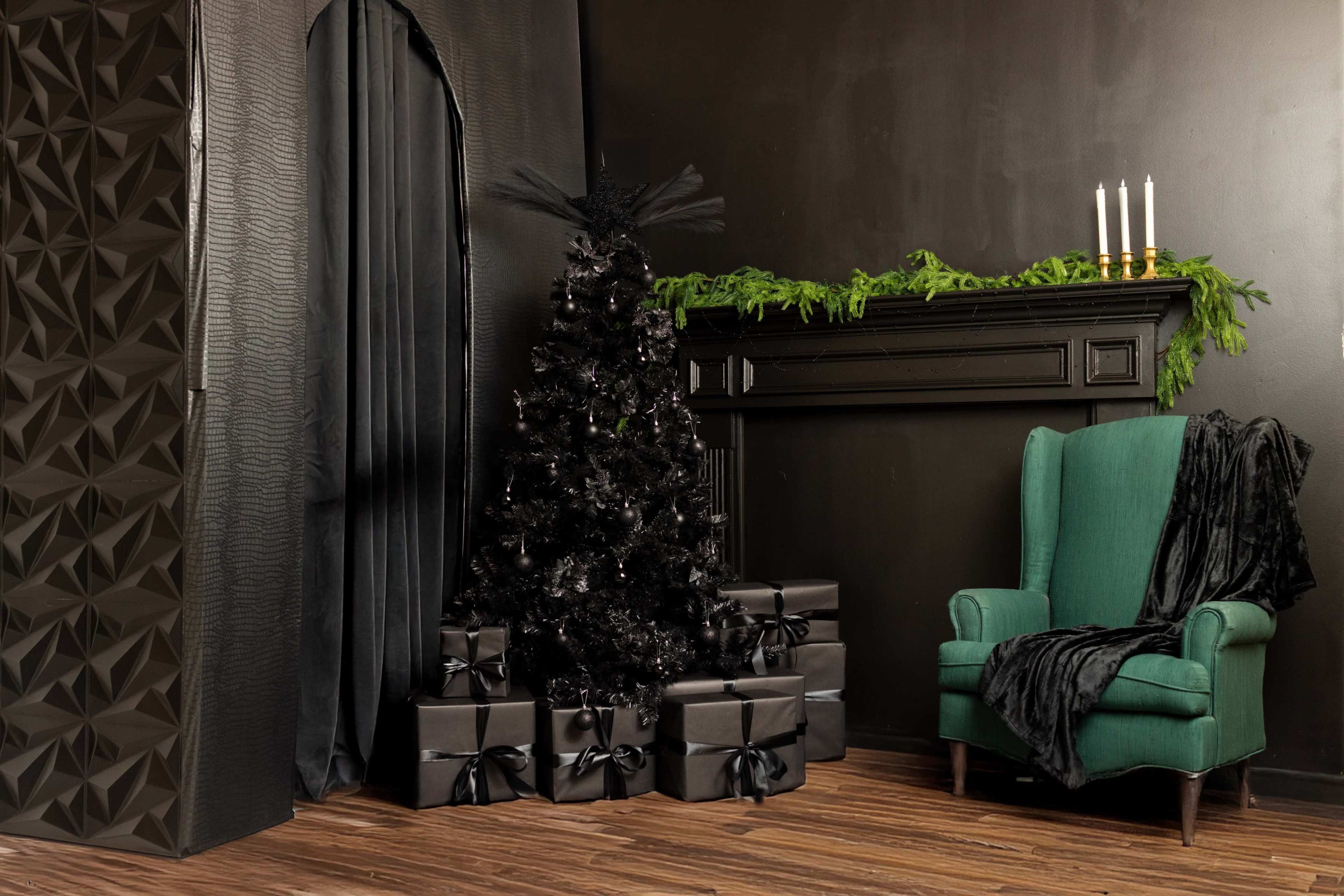The image features a black Christmas tree adorned with decorations, surrounded by black gift boxes with ribbons, in a dark room with a green armchair and a black mantle adorned with candles.
