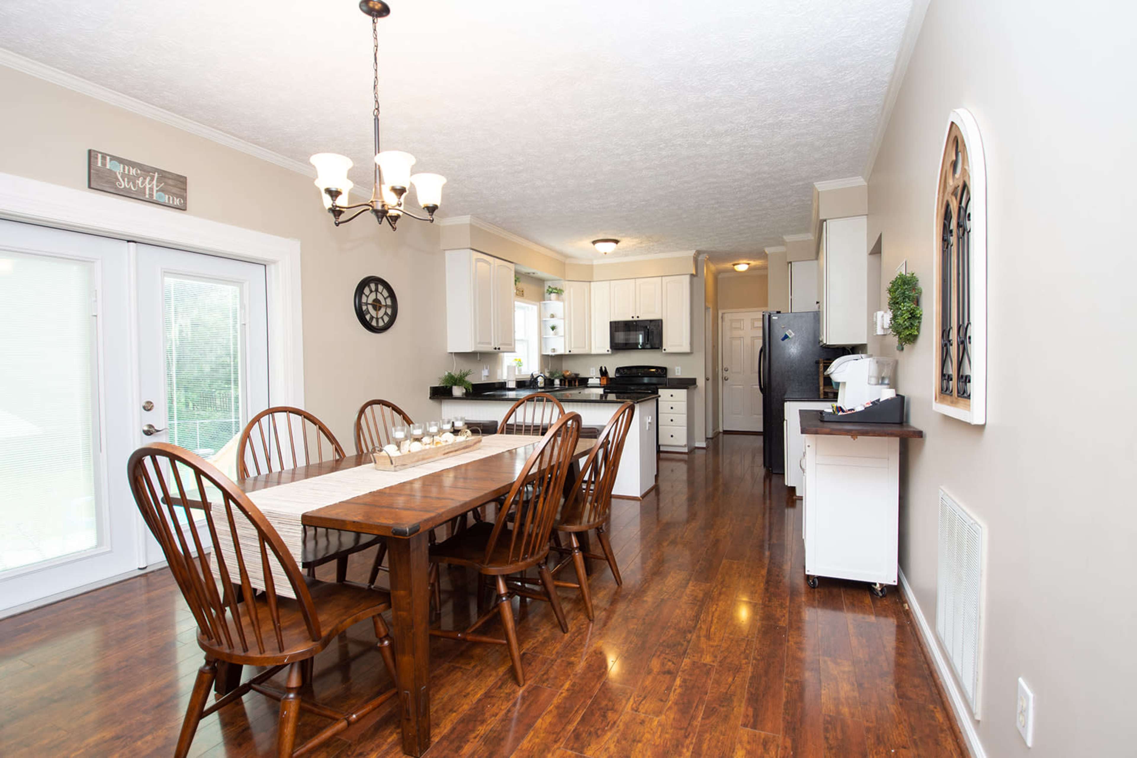 A spacious kitchen and dining area features a wooden table with chairs, modern appliances, and light-colored cabinetry.