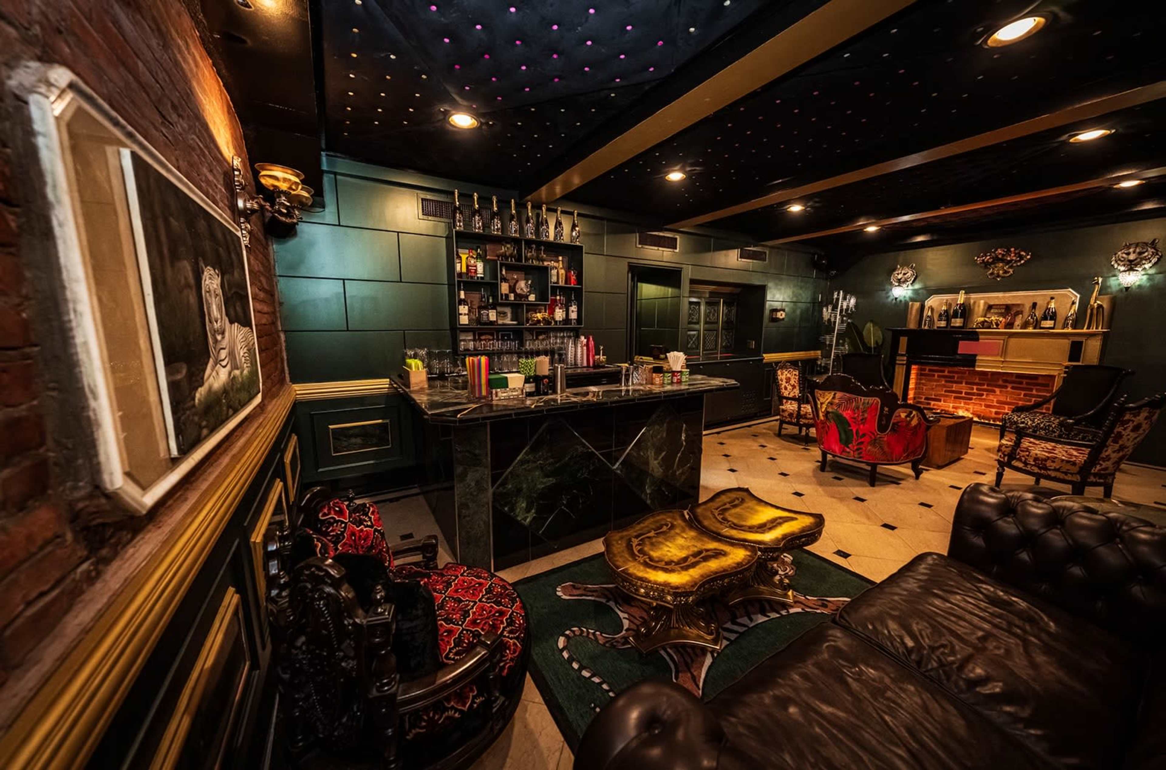 The image shows a stylish bar interior with a dark color scheme, featuring a marble bar counter, ornate seating, and decorative lighting.