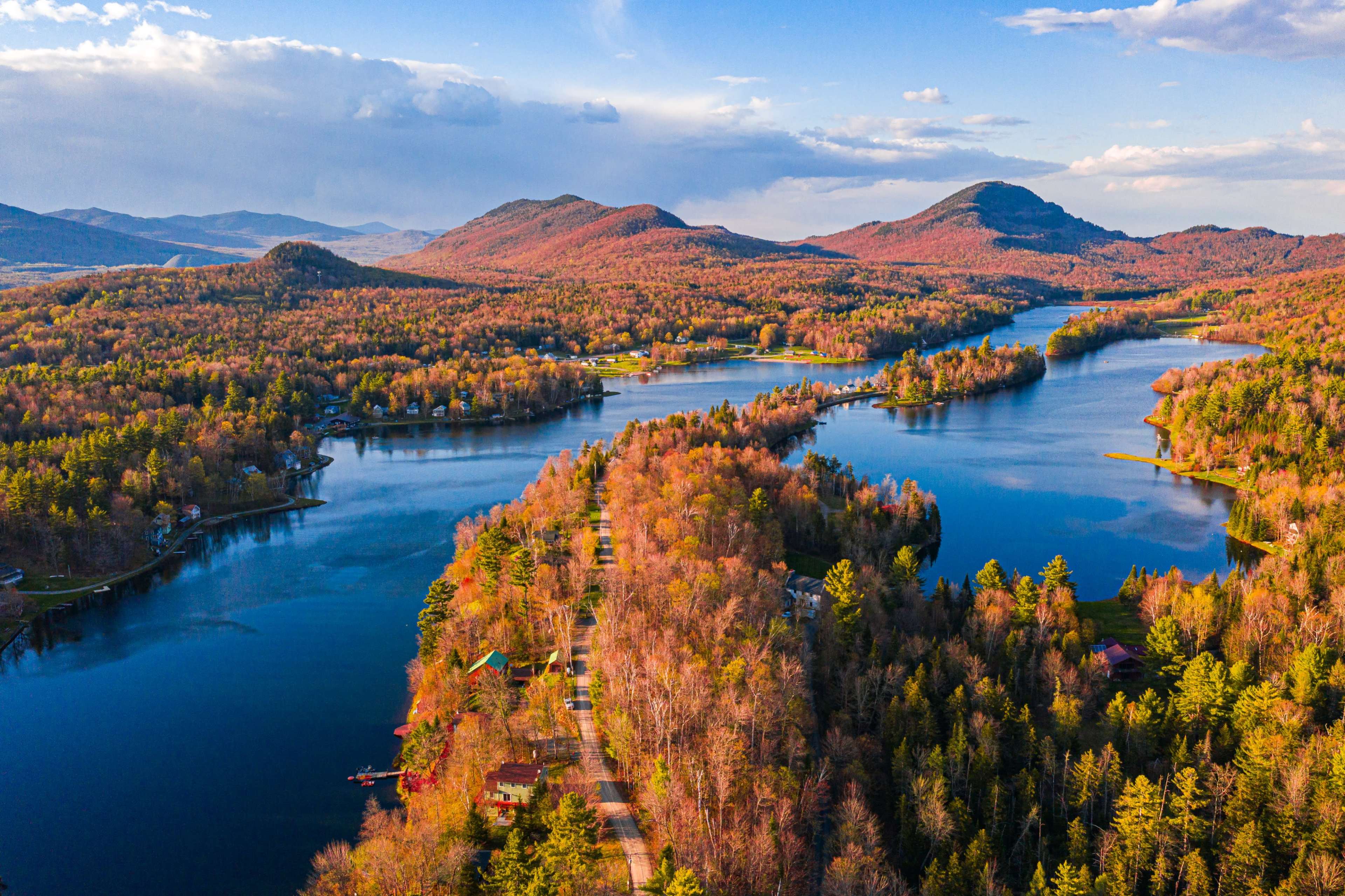 Aerial view of a serene landscape featuring winding rivers and a forested area with colorful autumn foliage in the mountains.