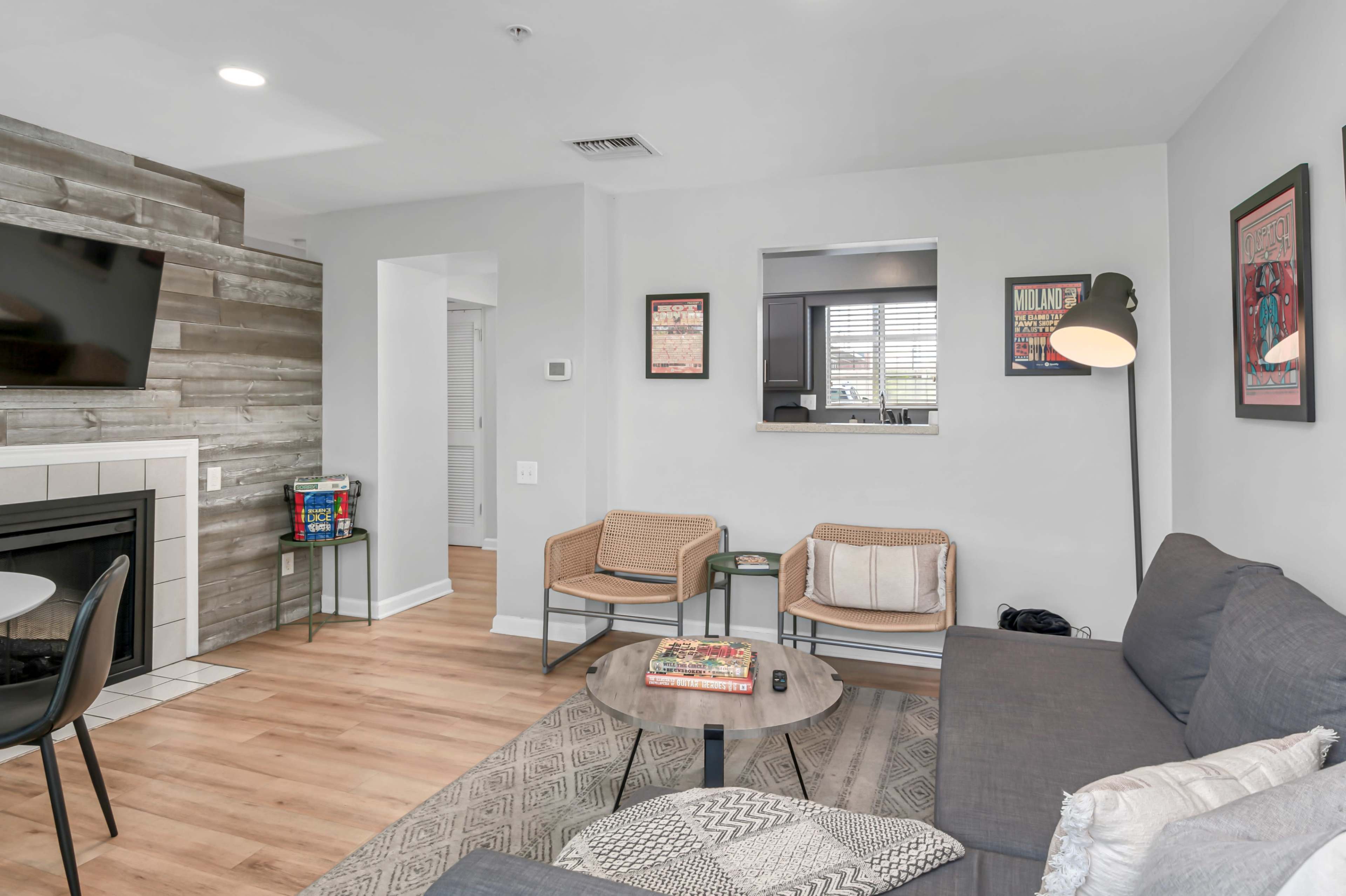 The living room features a gray sofa, a wooden coffee table, a fireplace, and a media unit with a television.