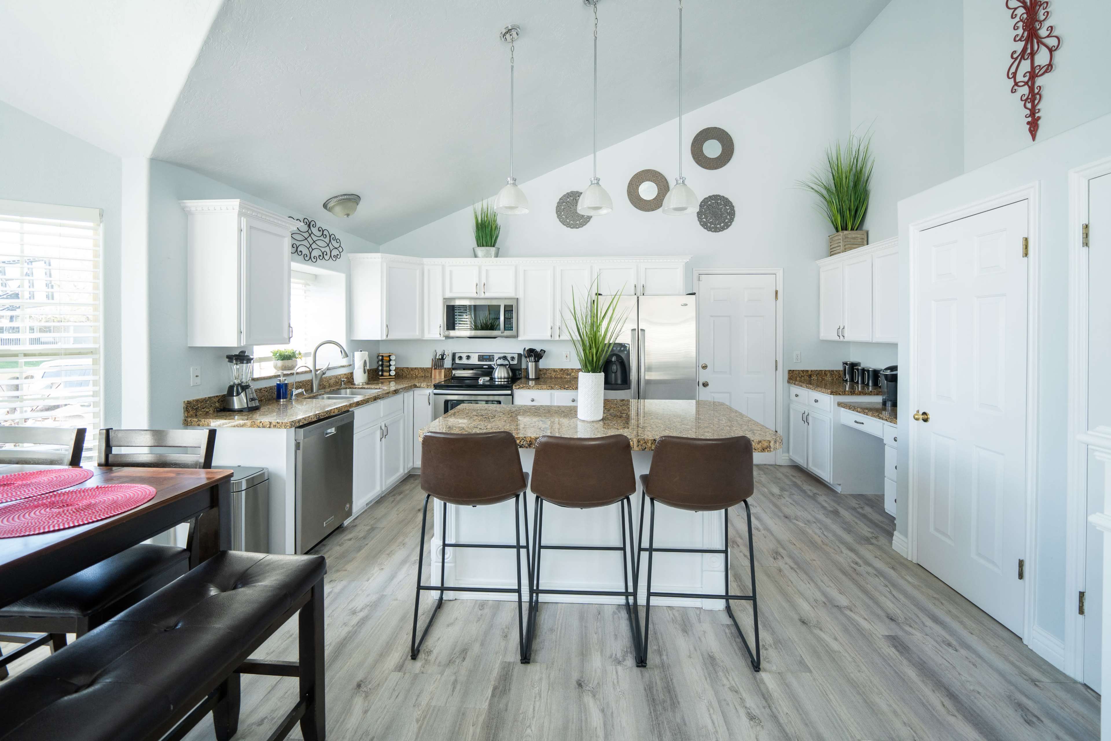 A modern kitchen features white cabinets, stainless steel appliances, and a large island with seating for three.