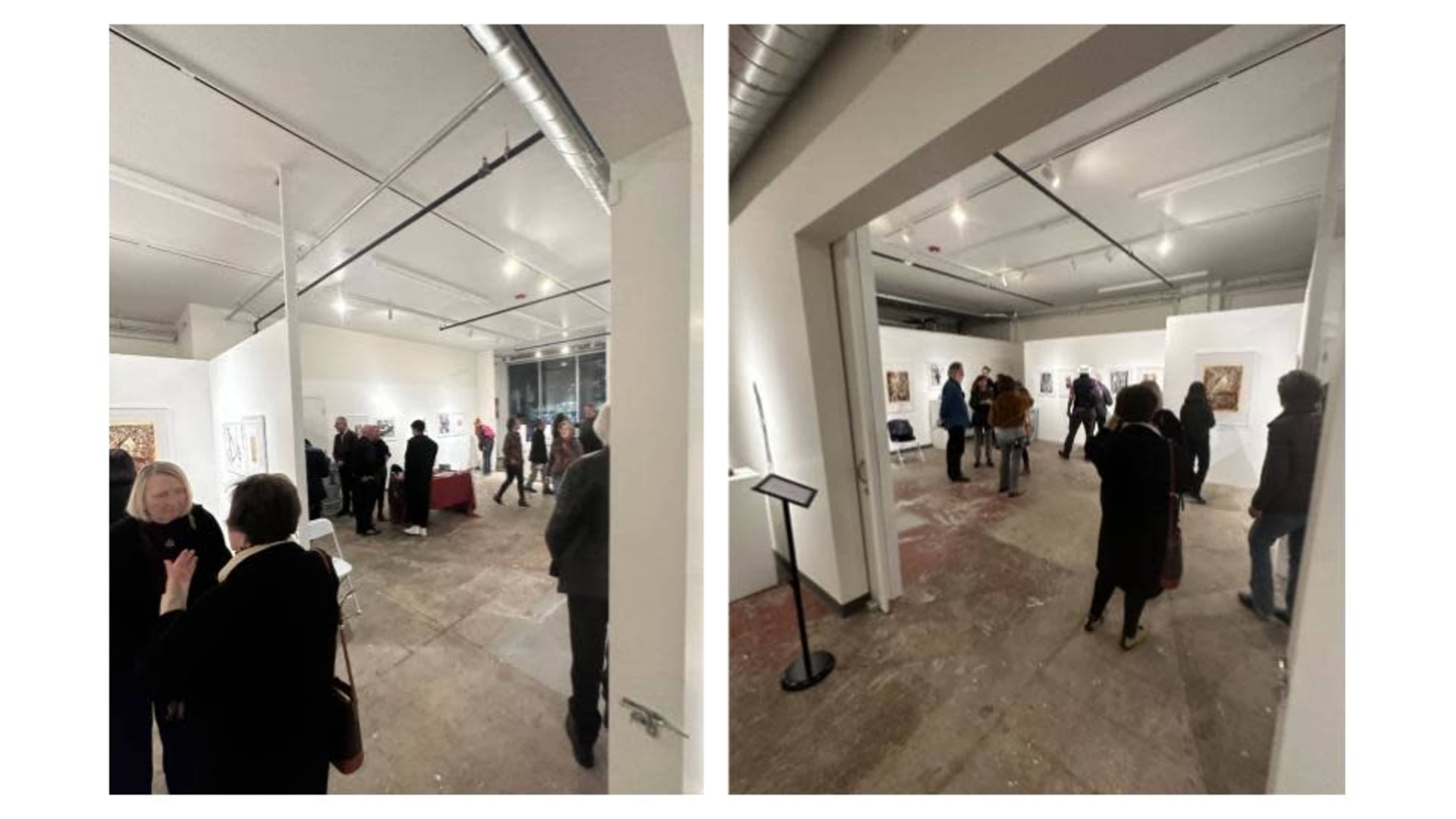 An art gallery with several people walking around and viewing artworks displayed on the walls.