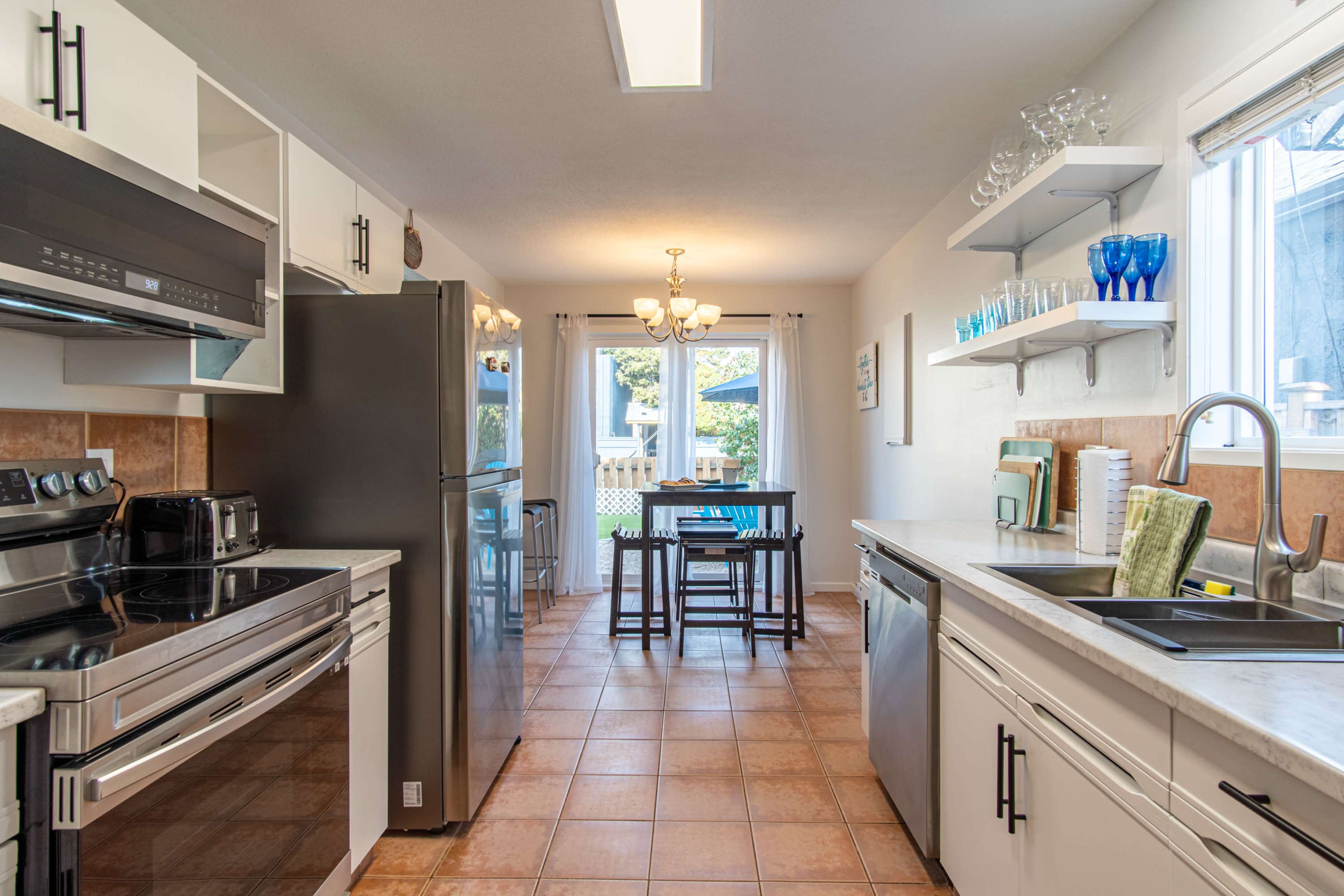 A modern kitchen features stainless steel appliances, light cabinetry, and a dining area with a table and chairs.