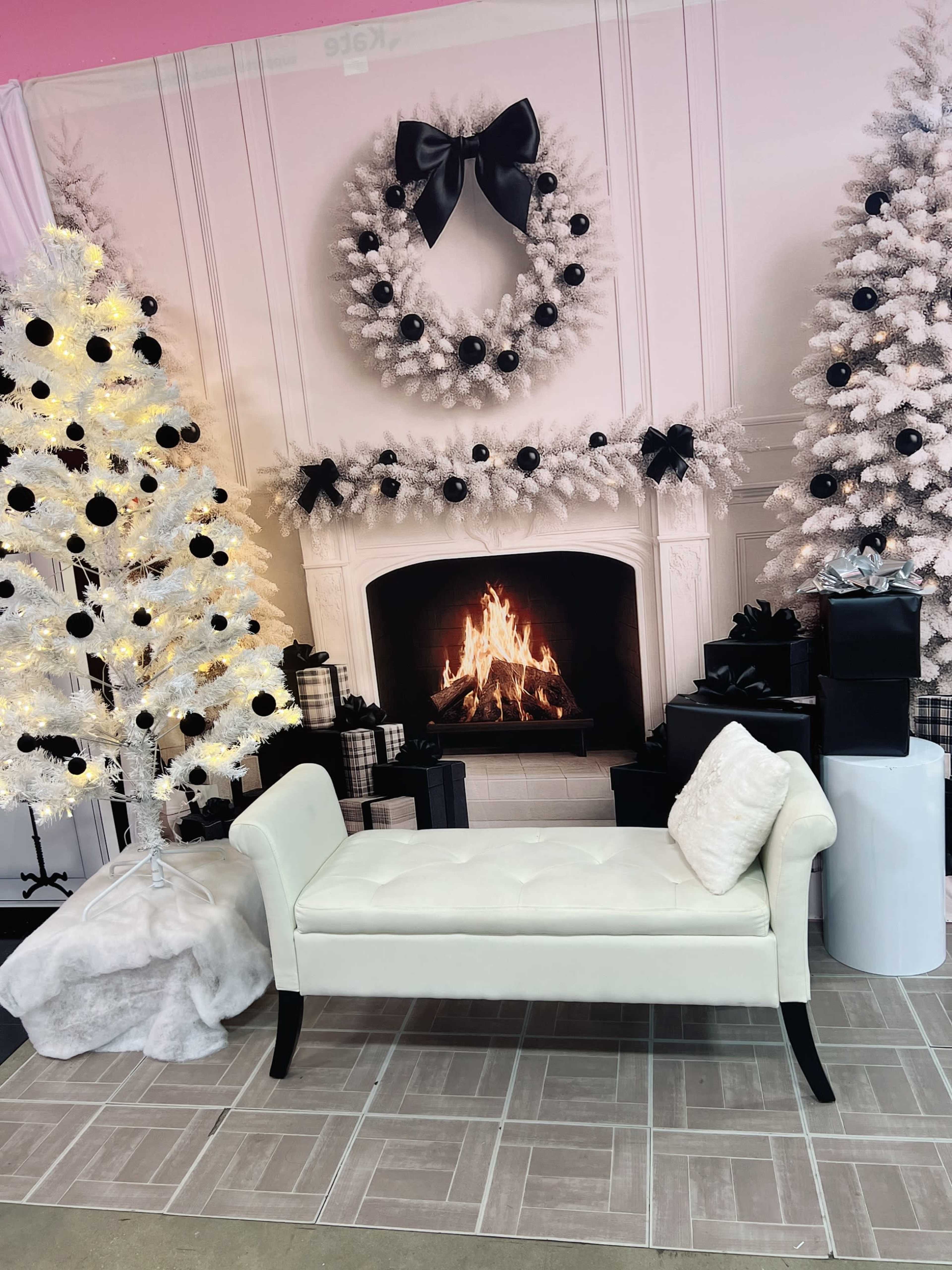 The scene features a white bench in front of a fireplace surrounded by a decorative Christmas setting, including a tree with lights and gifts.
