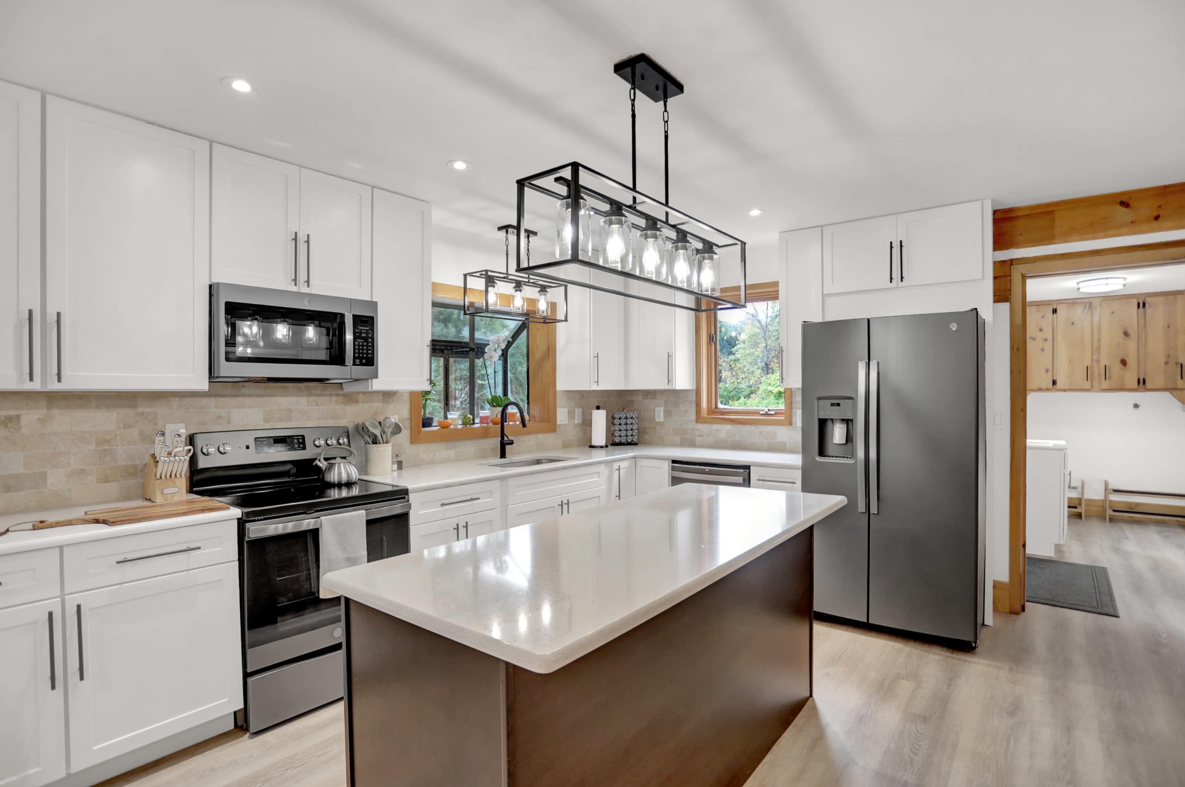 The kitchen features white cabinetry, stainless steel appliances, and a central island with a modern light fixture overhead.