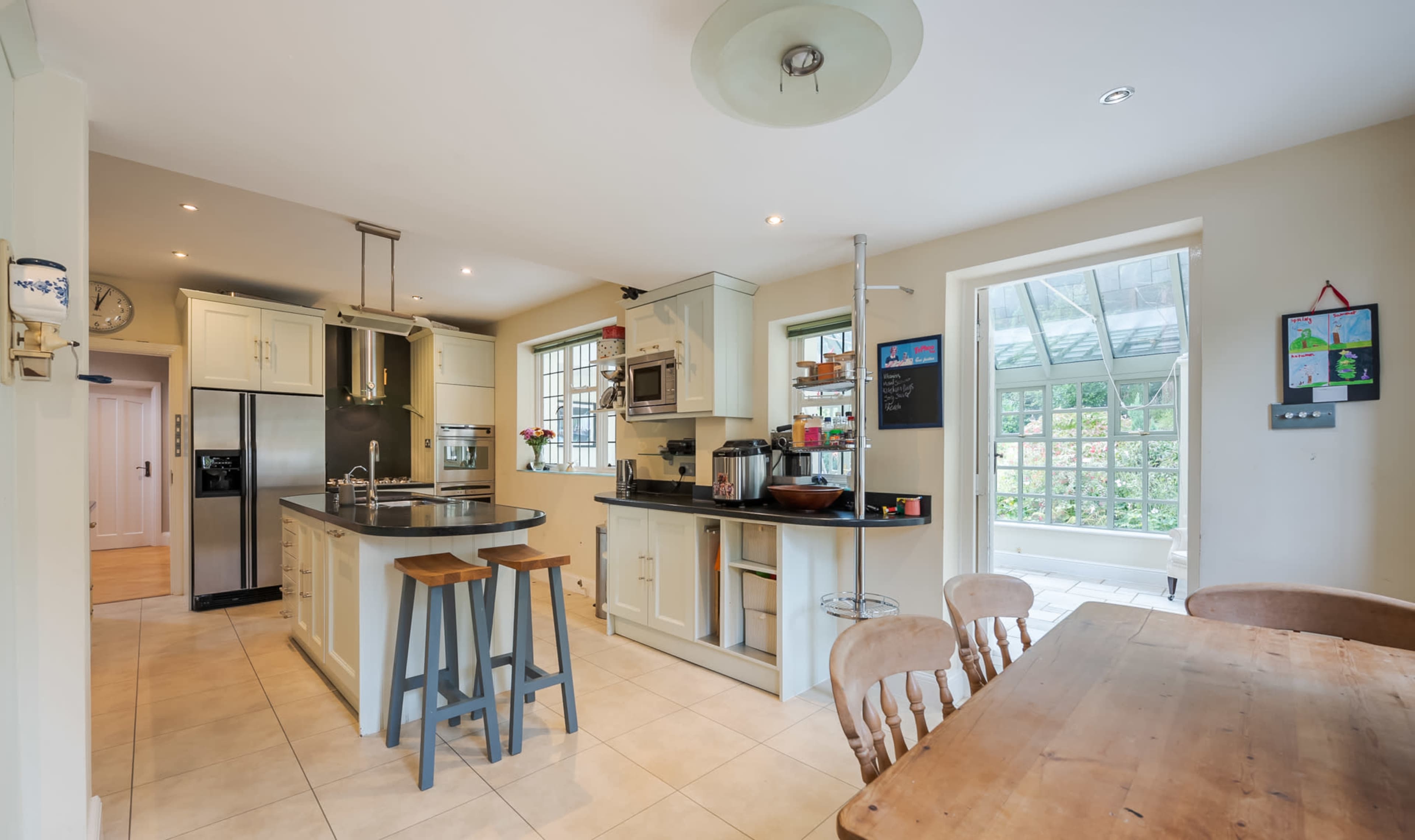 A modern kitchen with a central island, stainless steel appliances, and a dining area featuring a wooden table and chairs.