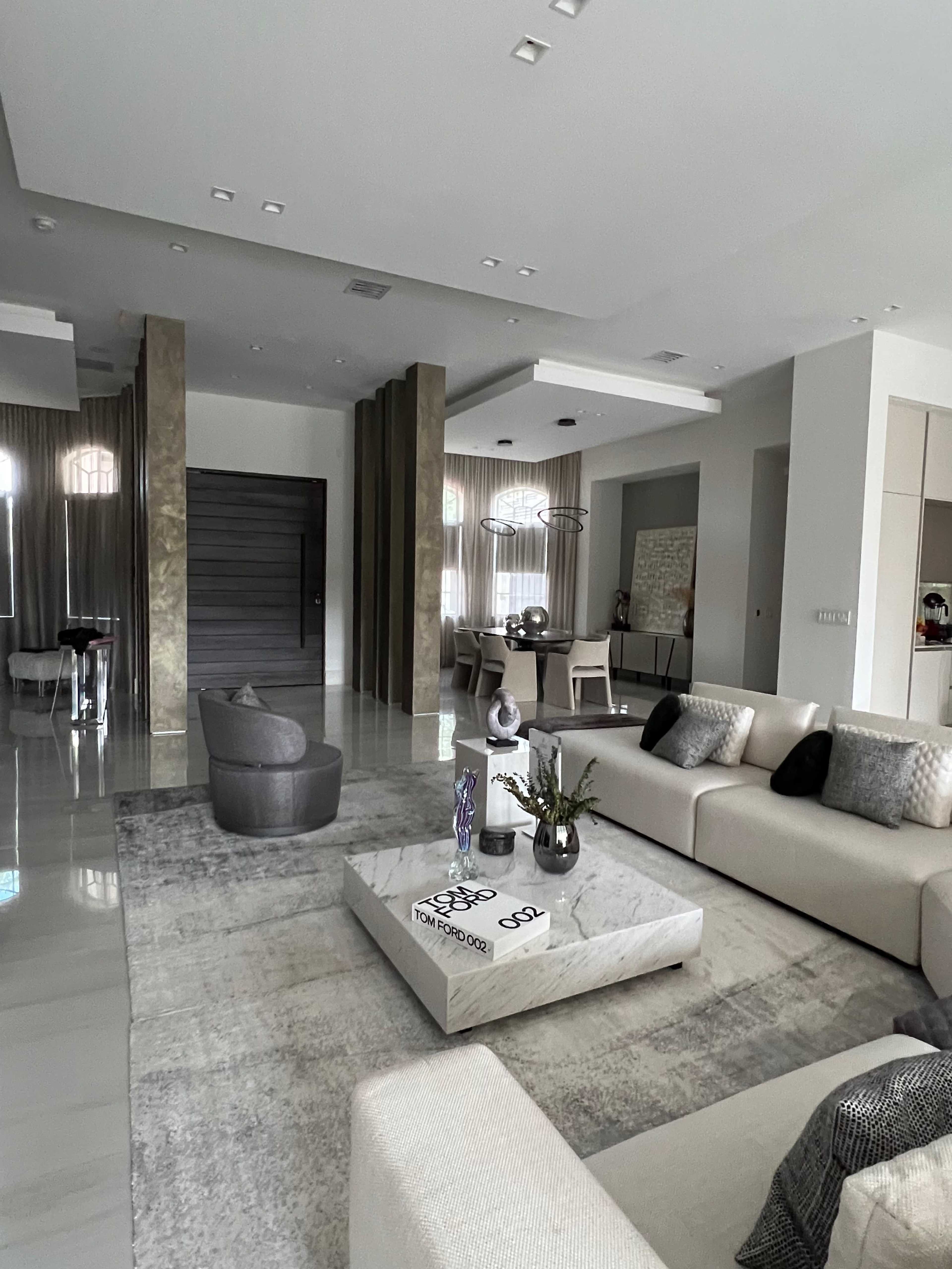 A modern living room featuring a large sectional sofa, a coffee table, and a combination of elegant furnishings set against neutral-colored walls and flooring.