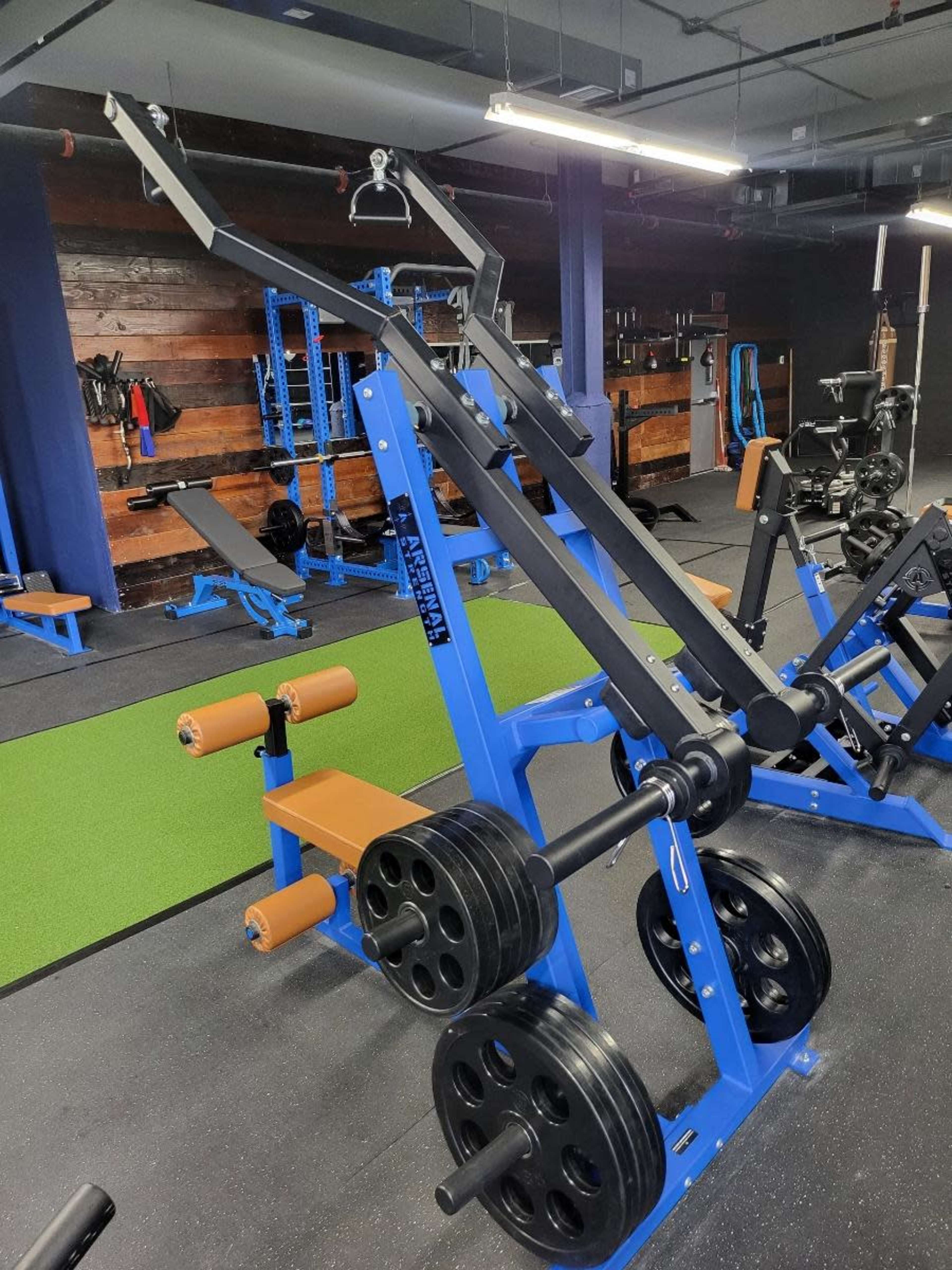 A blue weightlifting machine with a cable system and multiple weight plates in a gym setting.