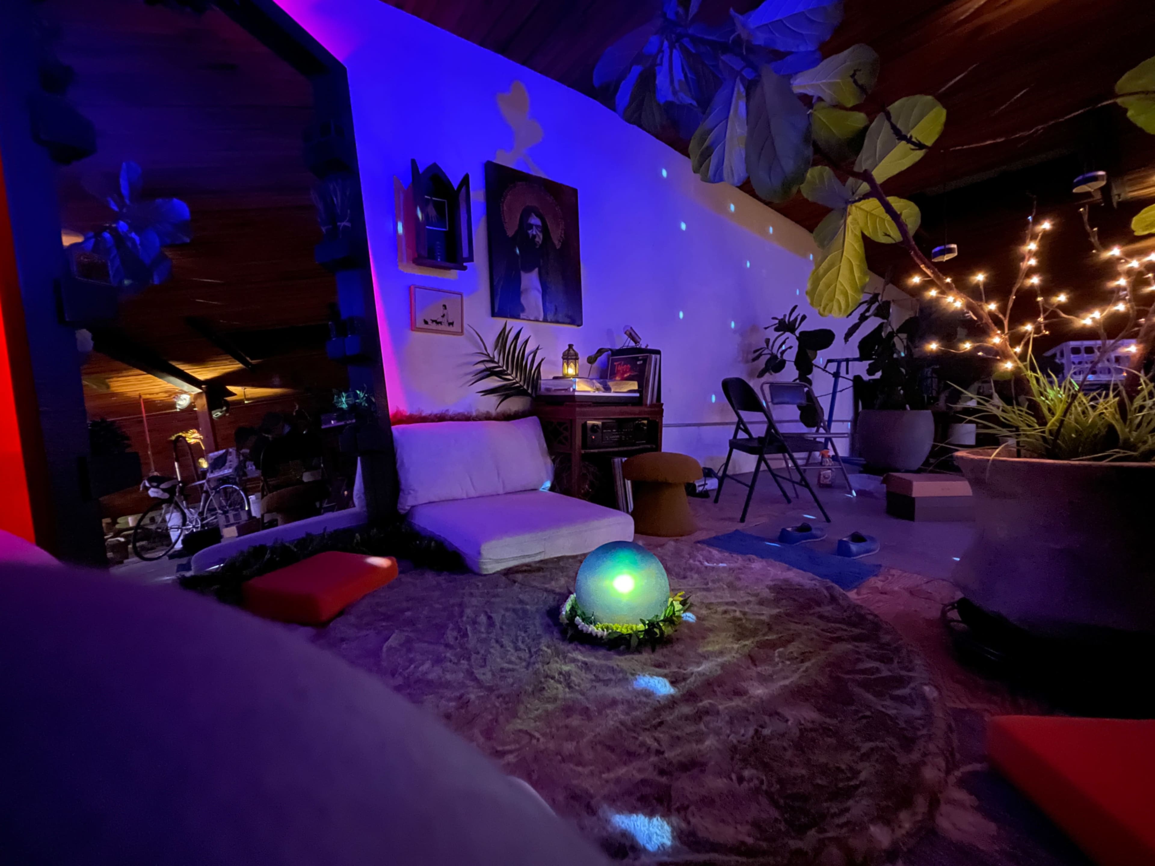 A cozy indoor space features a sofa, plants, and ambient lighting with a glowing orb in the center.