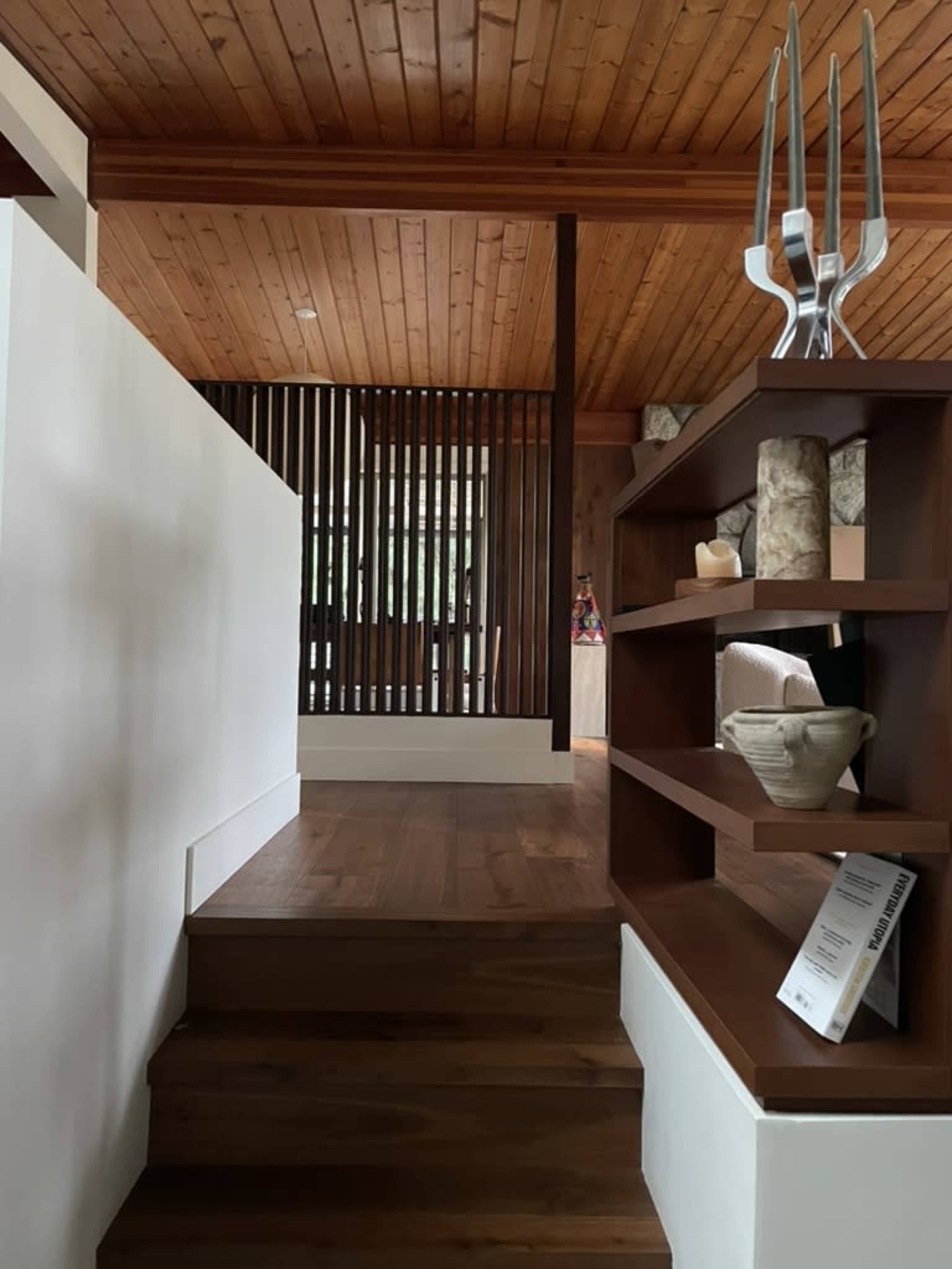 The image shows a wooden staircase leading to a living space with wood paneling and a partitioned wall.