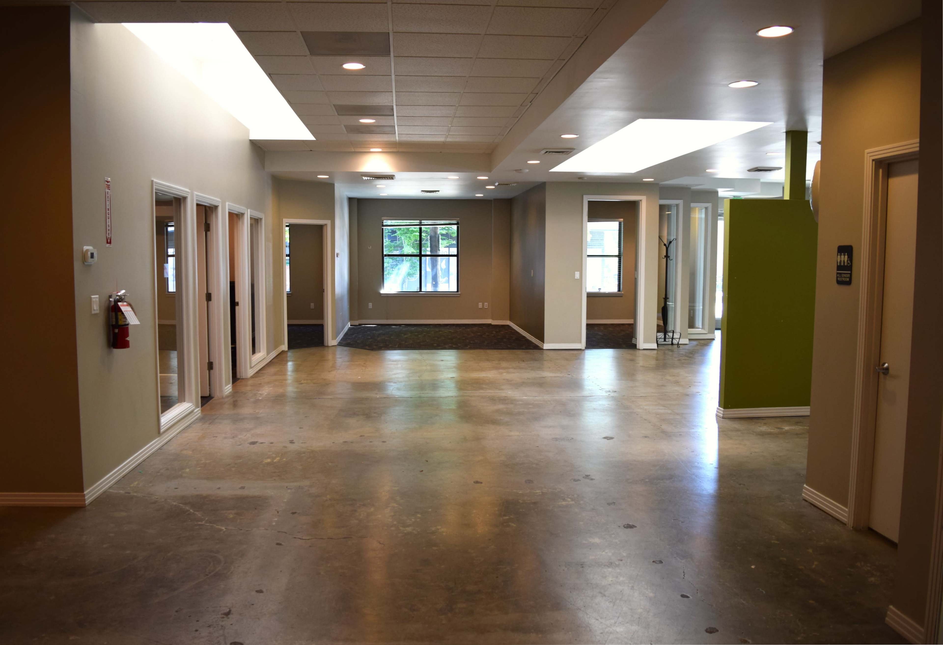 The image shows a spacious interior hallway with several doorways, a window at the end, and a green accent wall.