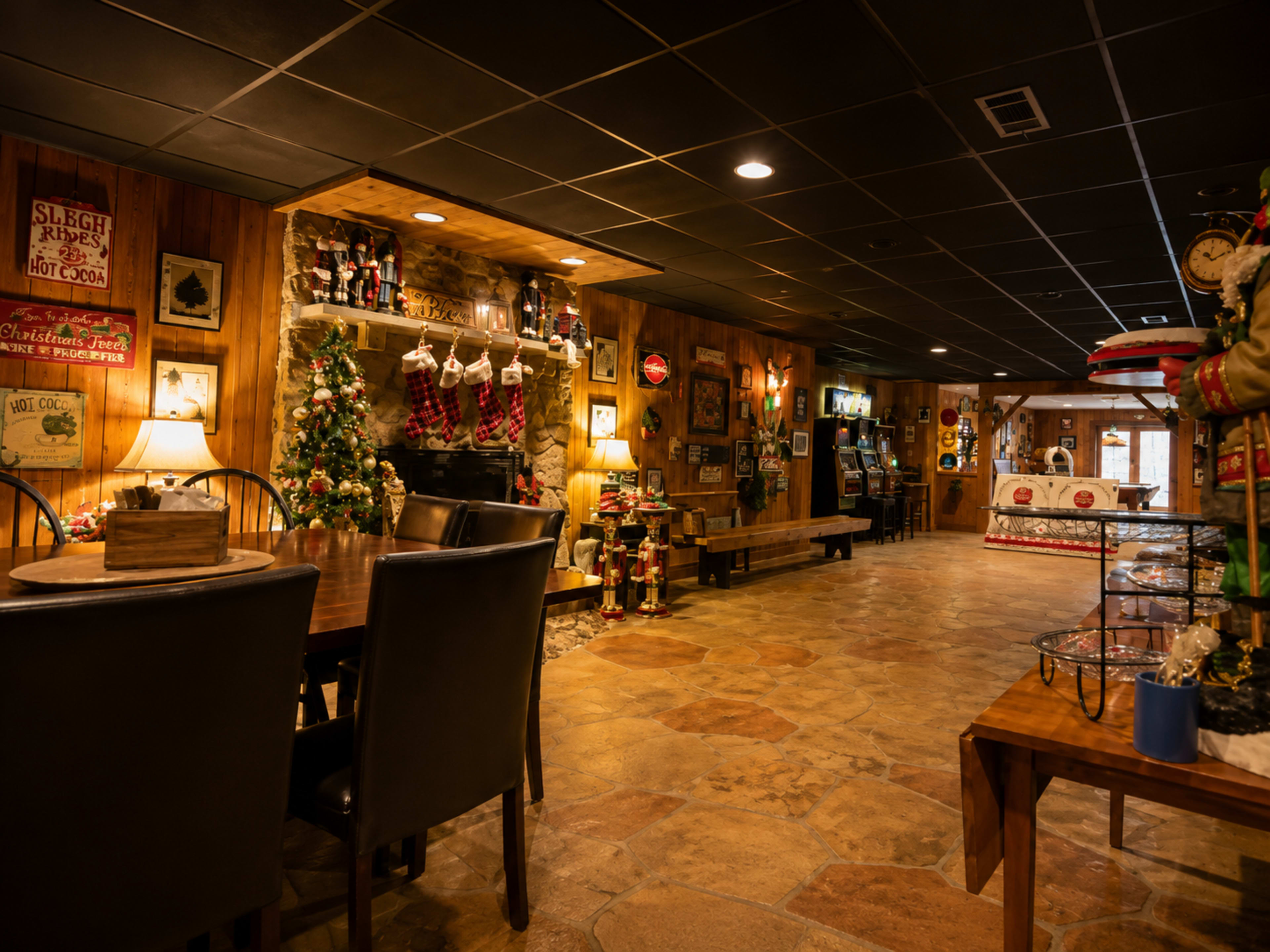 The image shows a cozy indoor dining area with wooden decor, a Christmas tree, and festive decorations along the walls.
