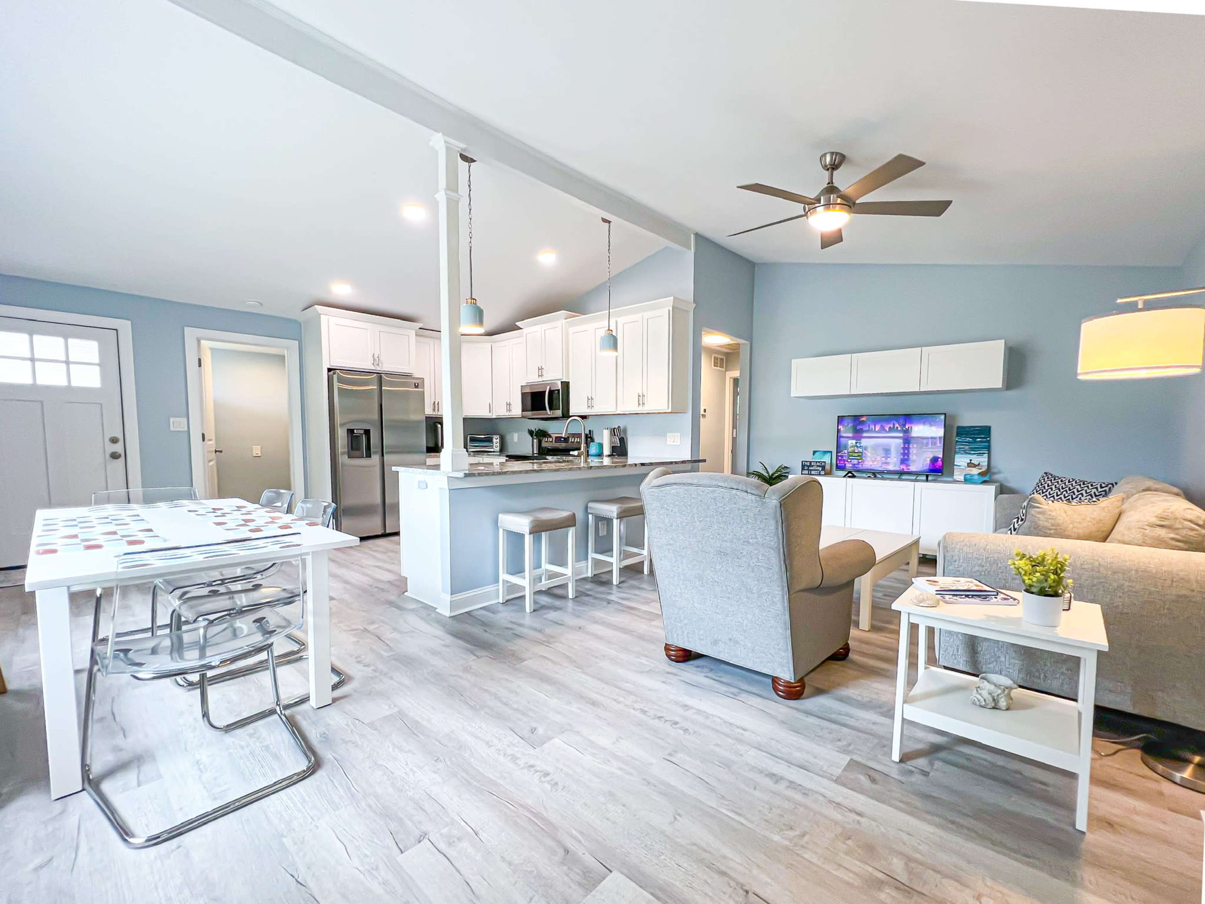 A modern living space featuring a kitchen, dining area with a table, and a cozy seating arrangement near a television.
