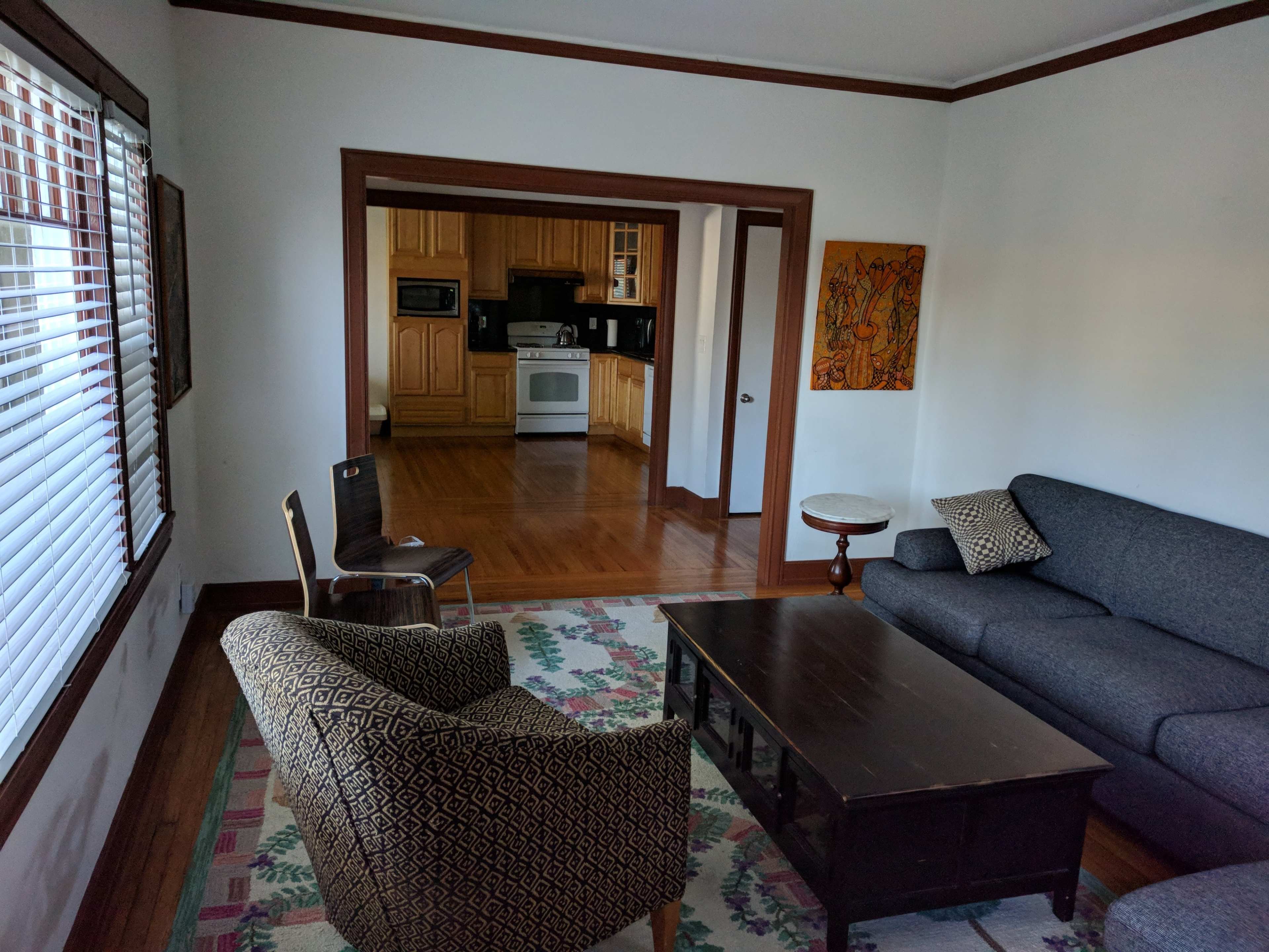 A living room with a sofa, two chairs, a coffee table, and a view of a kitchen in the background.