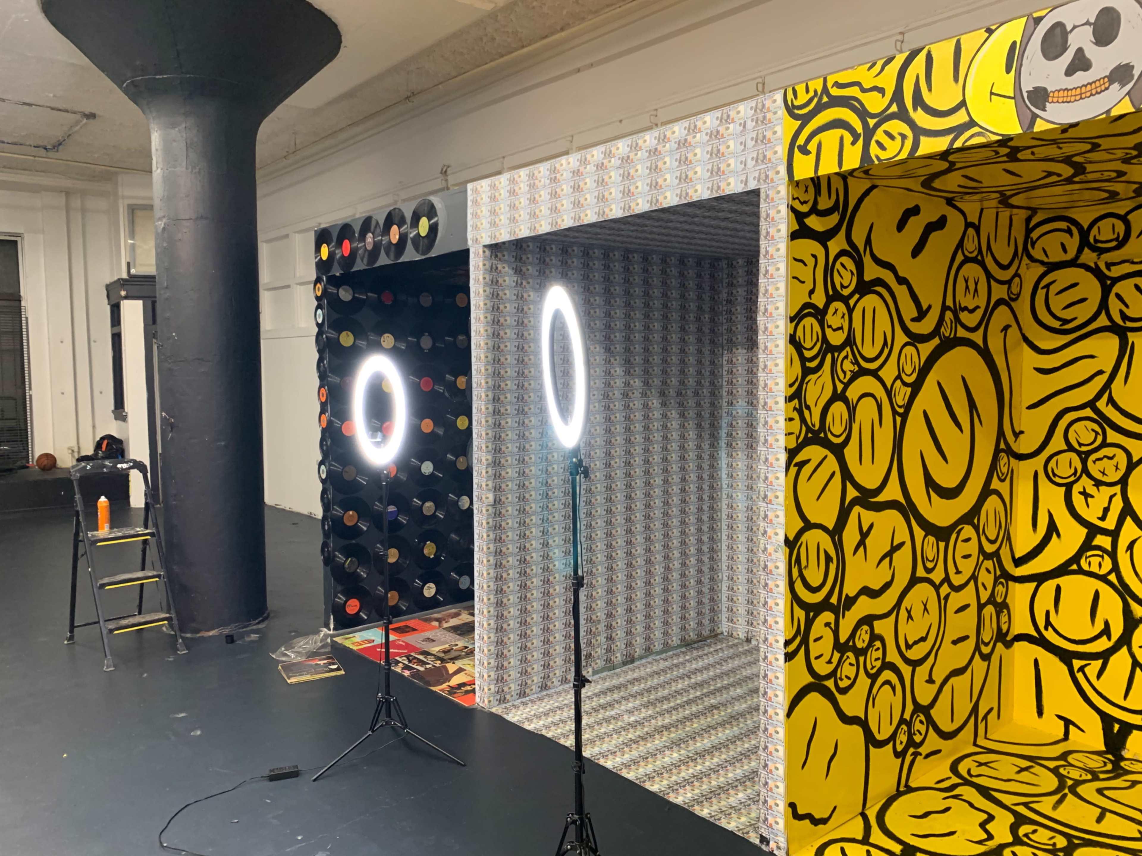 A room with three alcoves featuring patterned backgrounds, two ring lights on stands, and a stool nearby.