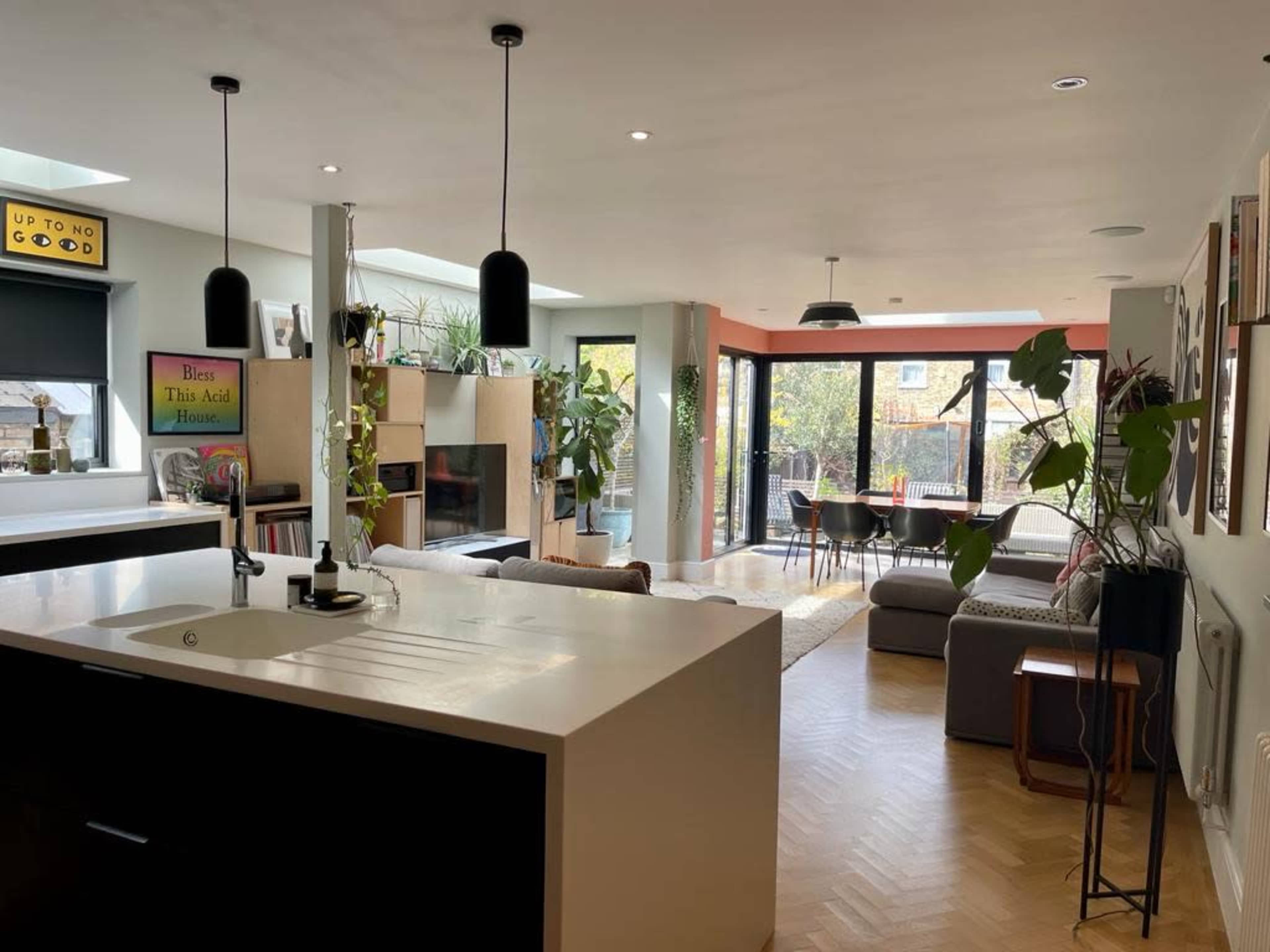 An open-concept living space with a modern kitchen on the left and a furnished lounge area with large windows on the right.
