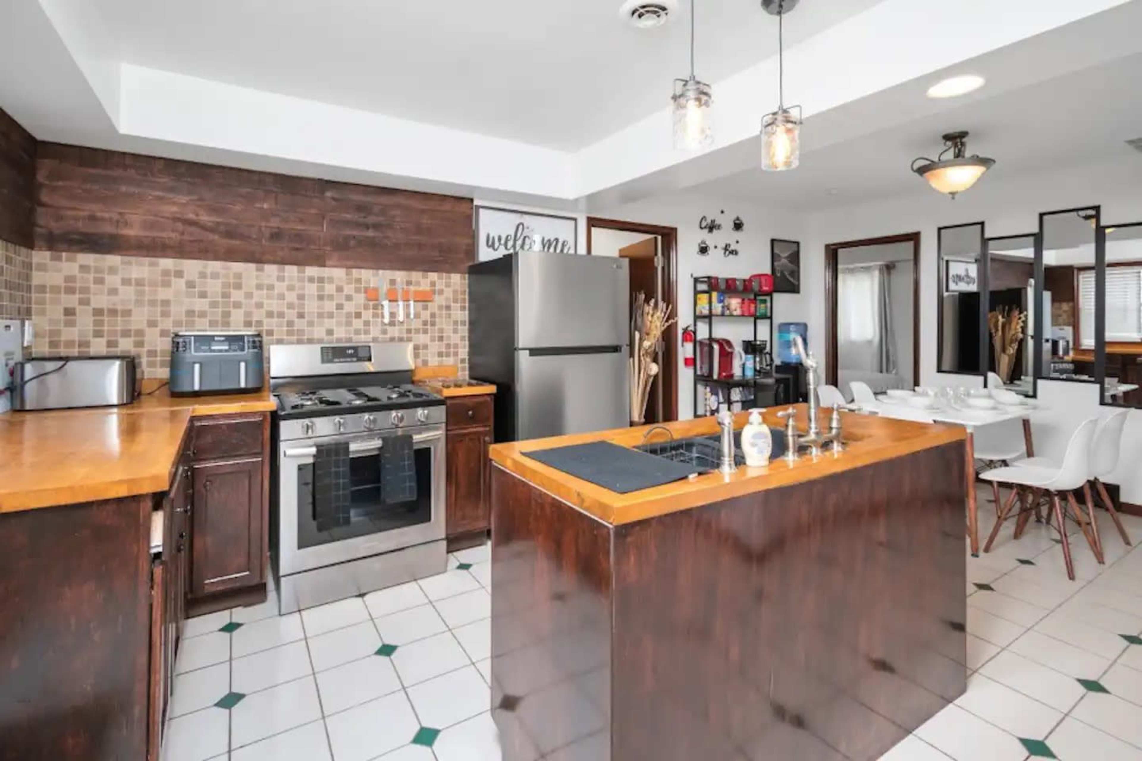 A modern kitchen with wooden cabinetry, stainless steel appliances, and a central island with a sink.