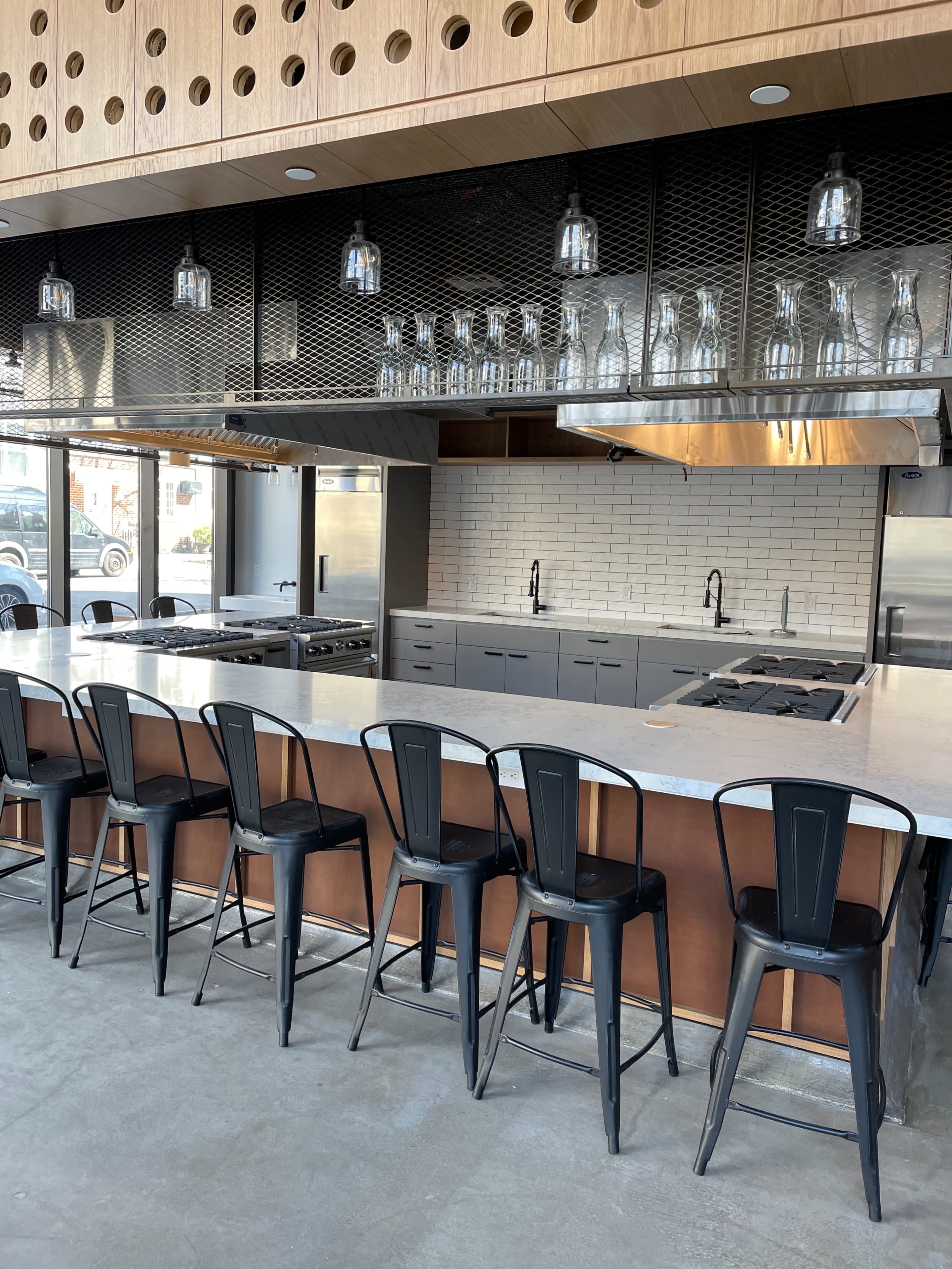 A modern kitchen with a large island, bar stools, and stainless steel appliances, featuring a sleek design and open layout.