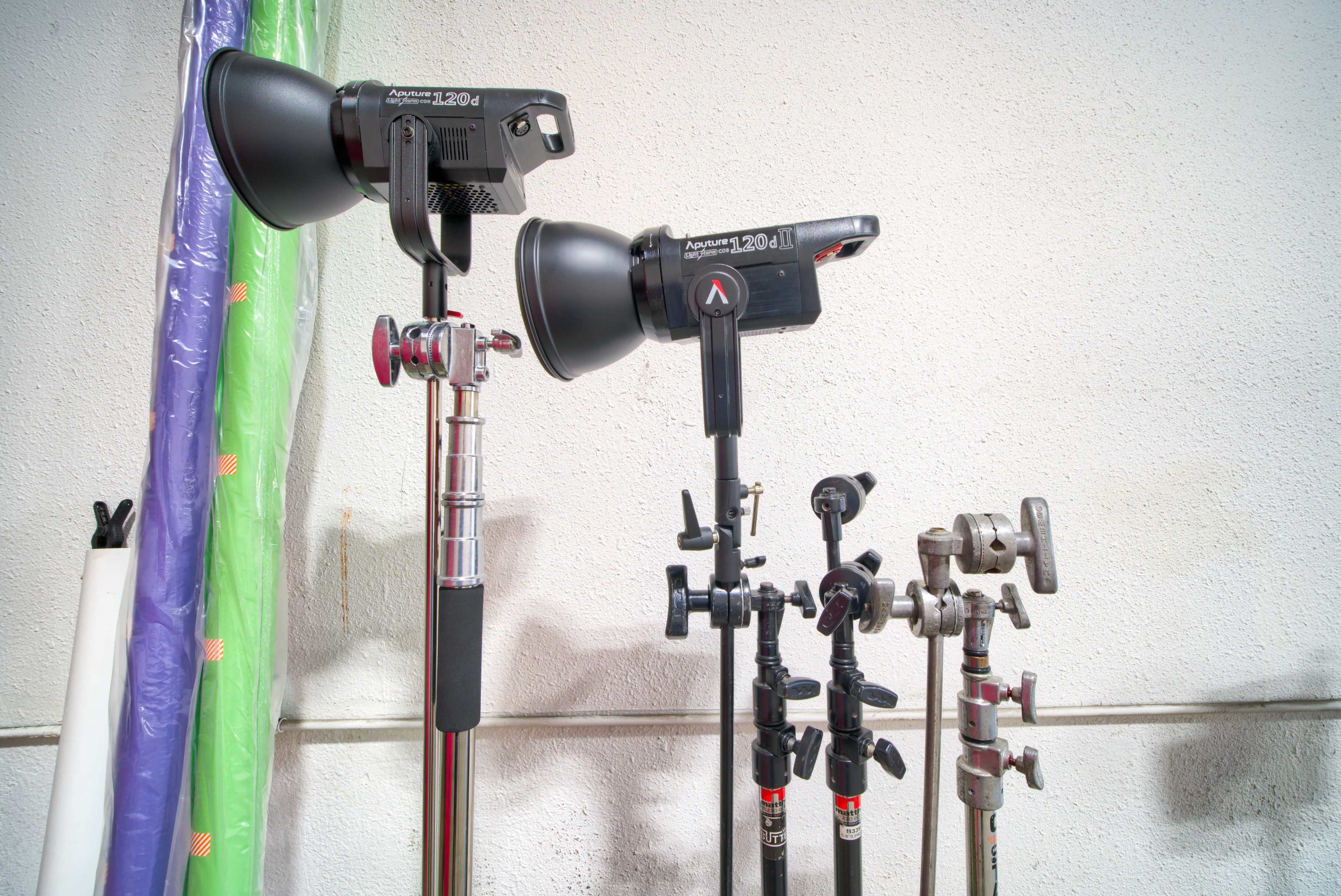 The image shows two lighting equipment stands with softboxes attached, alongside several other light stands in a studio setting.