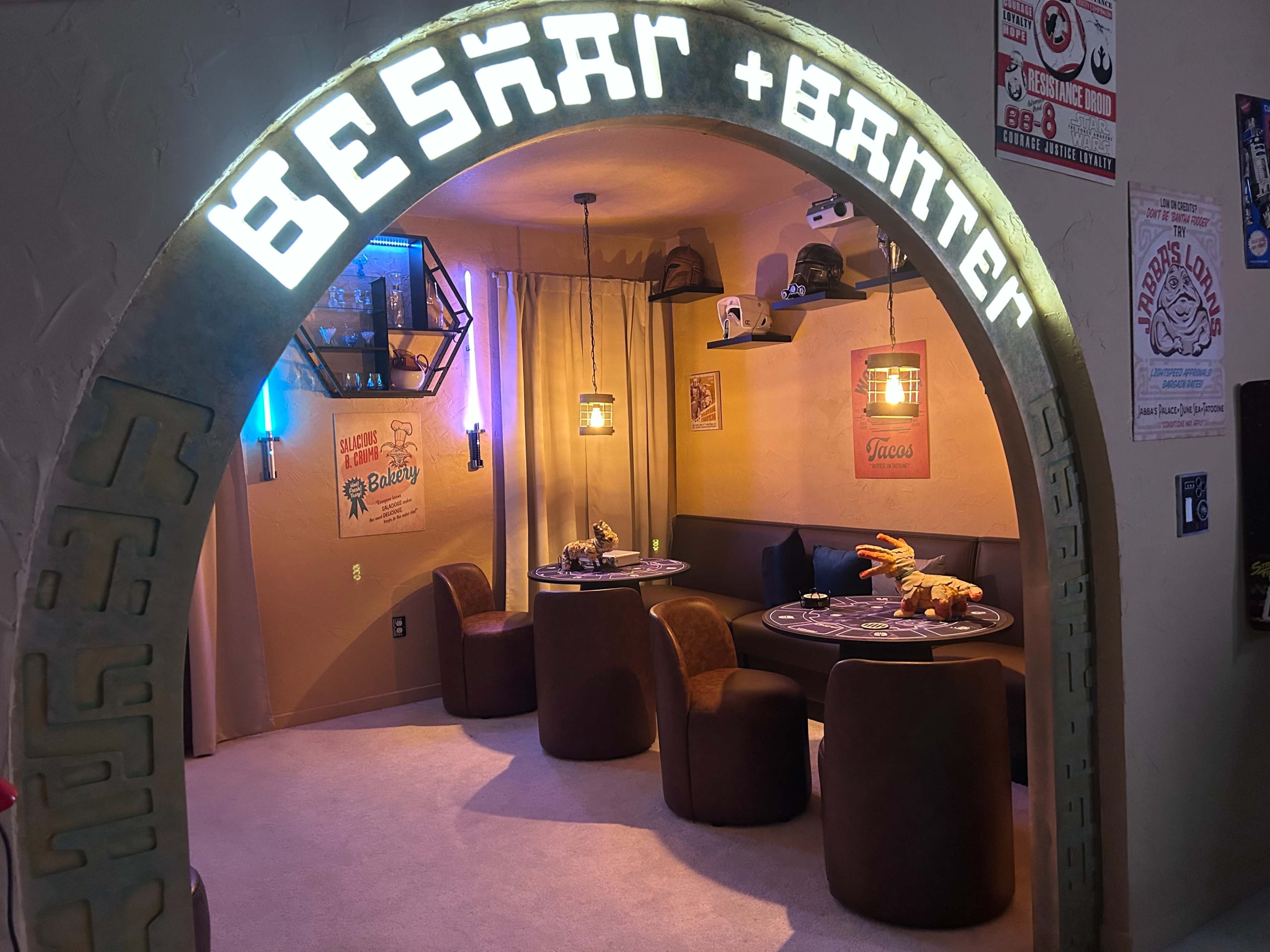 The image shows a themed interior space with an arched entrance marked "BESKAR + BANTER," featuring cozy seating areas and decorative elements on the walls.