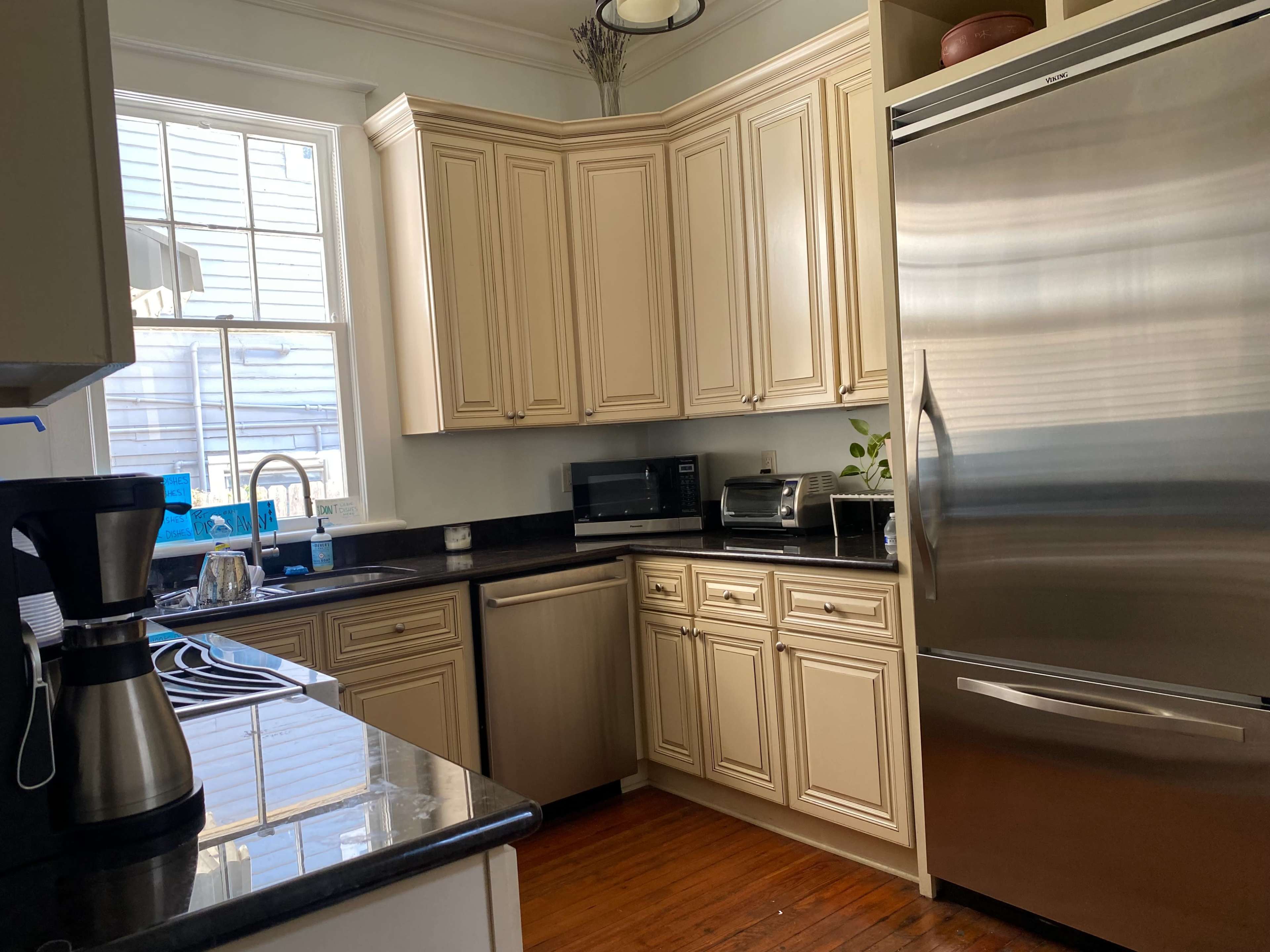 A modern kitchen featuring beige cabinetry, stainless steel appliances, and a window allowing natural light to illuminate the space.