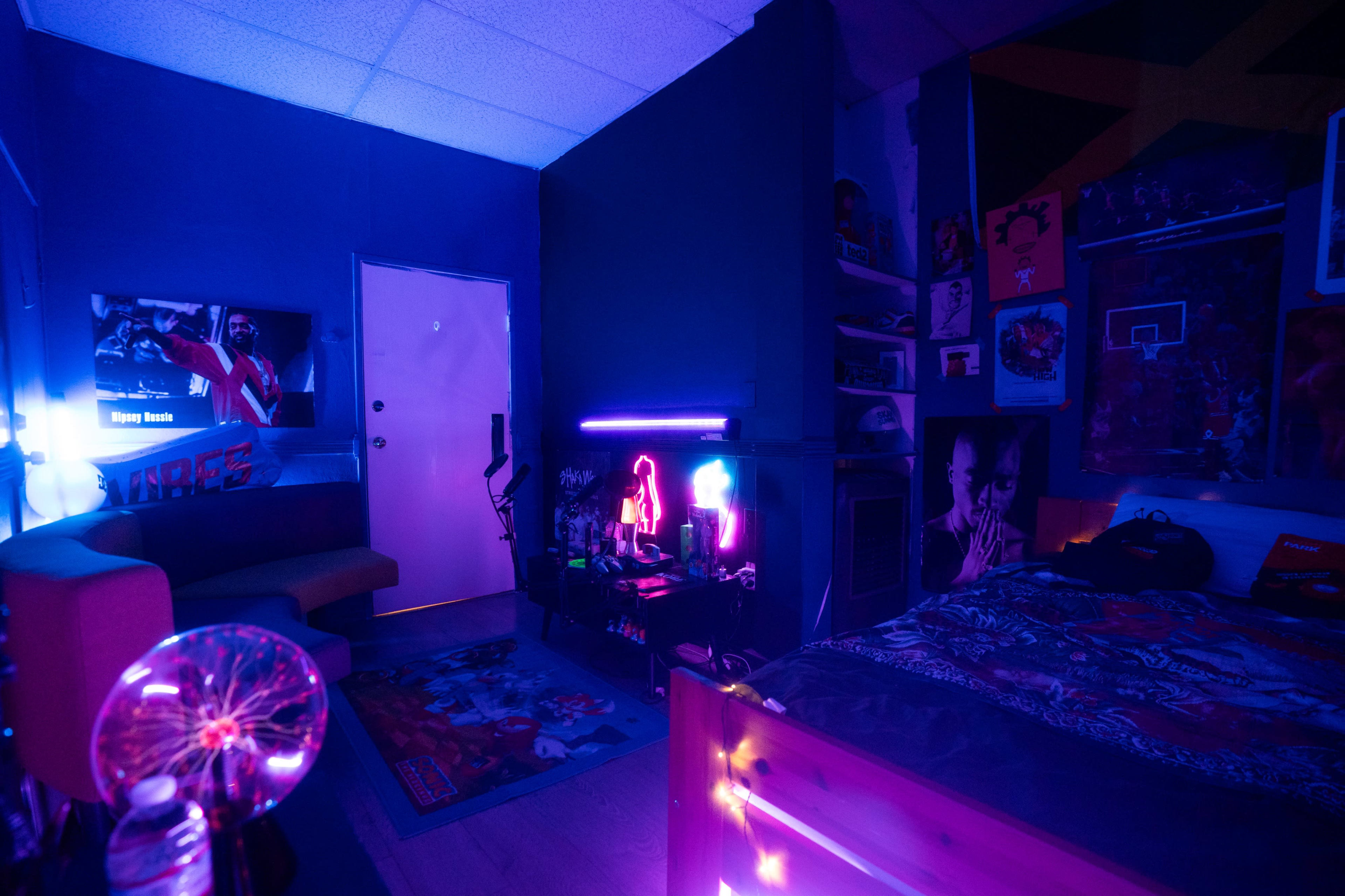 The room features a sofa, a bed with colorful bedding, and various decorations illuminated by neon lights, creating a vibrant atmosphere.