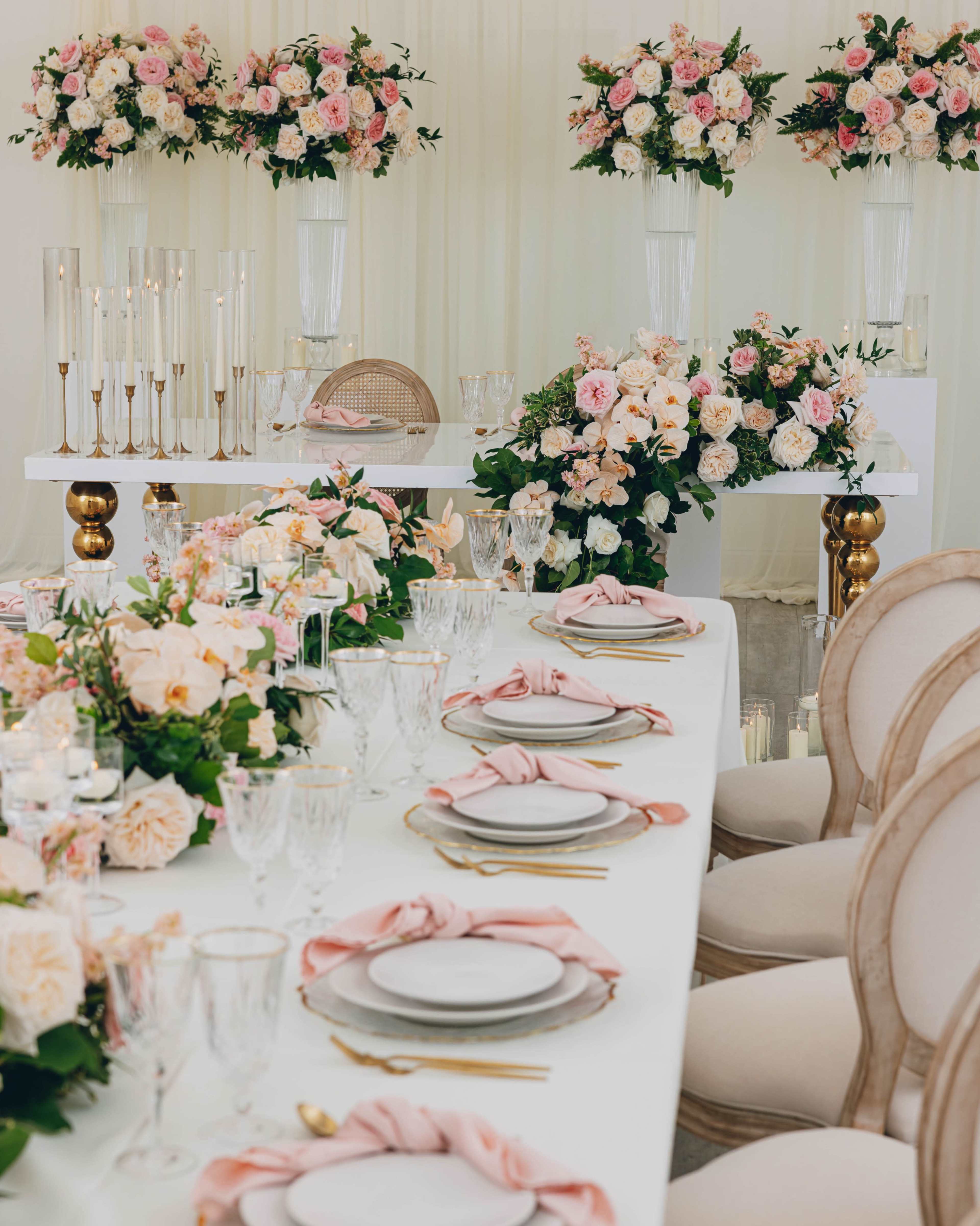 A elegantly set dining table adorned with floral arrangements and decorative tableware in a spacious, well-lit venue.