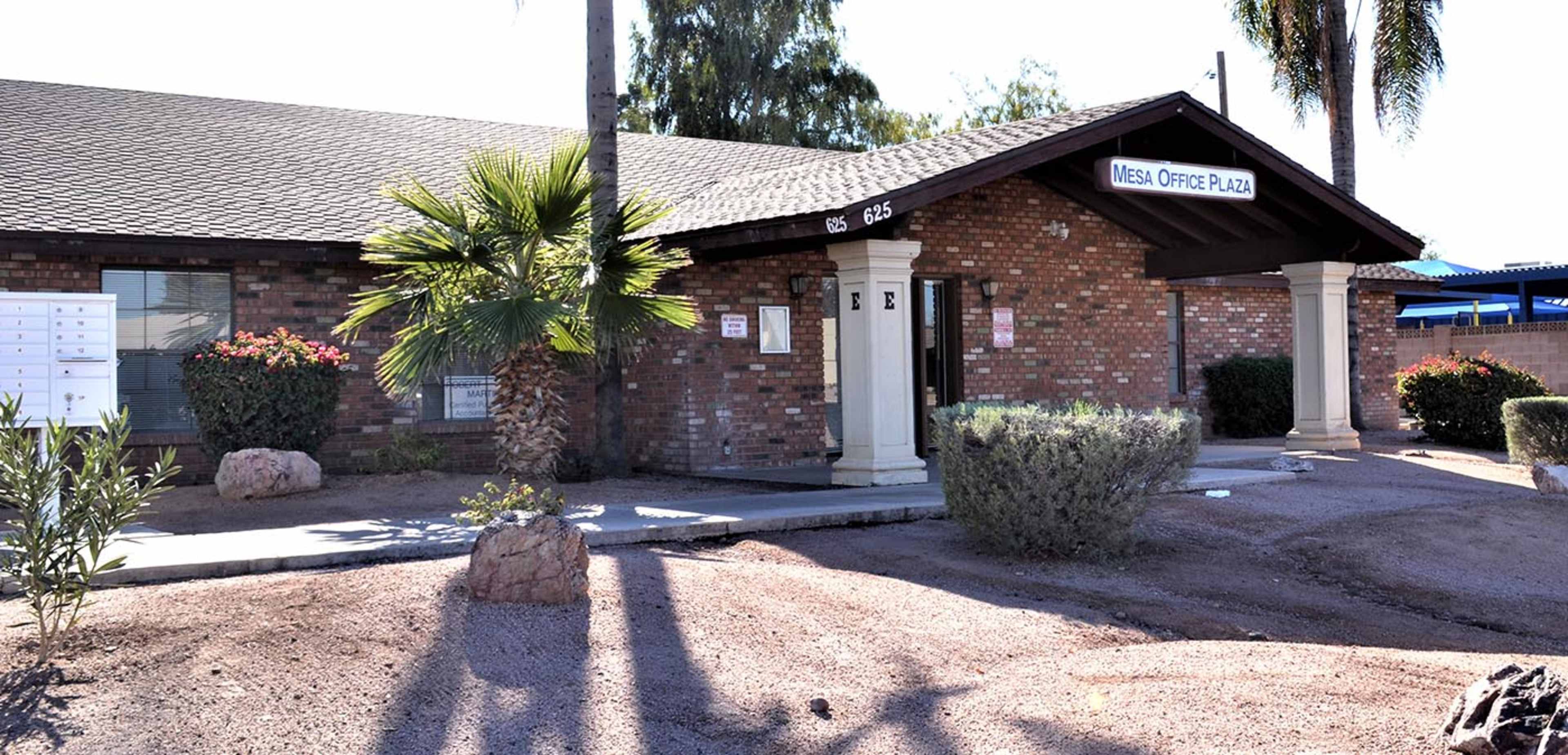 The image shows a brick office building with a sign labeled "Mesa Office Plaza," surrounded by desert landscaping and mailboxes.