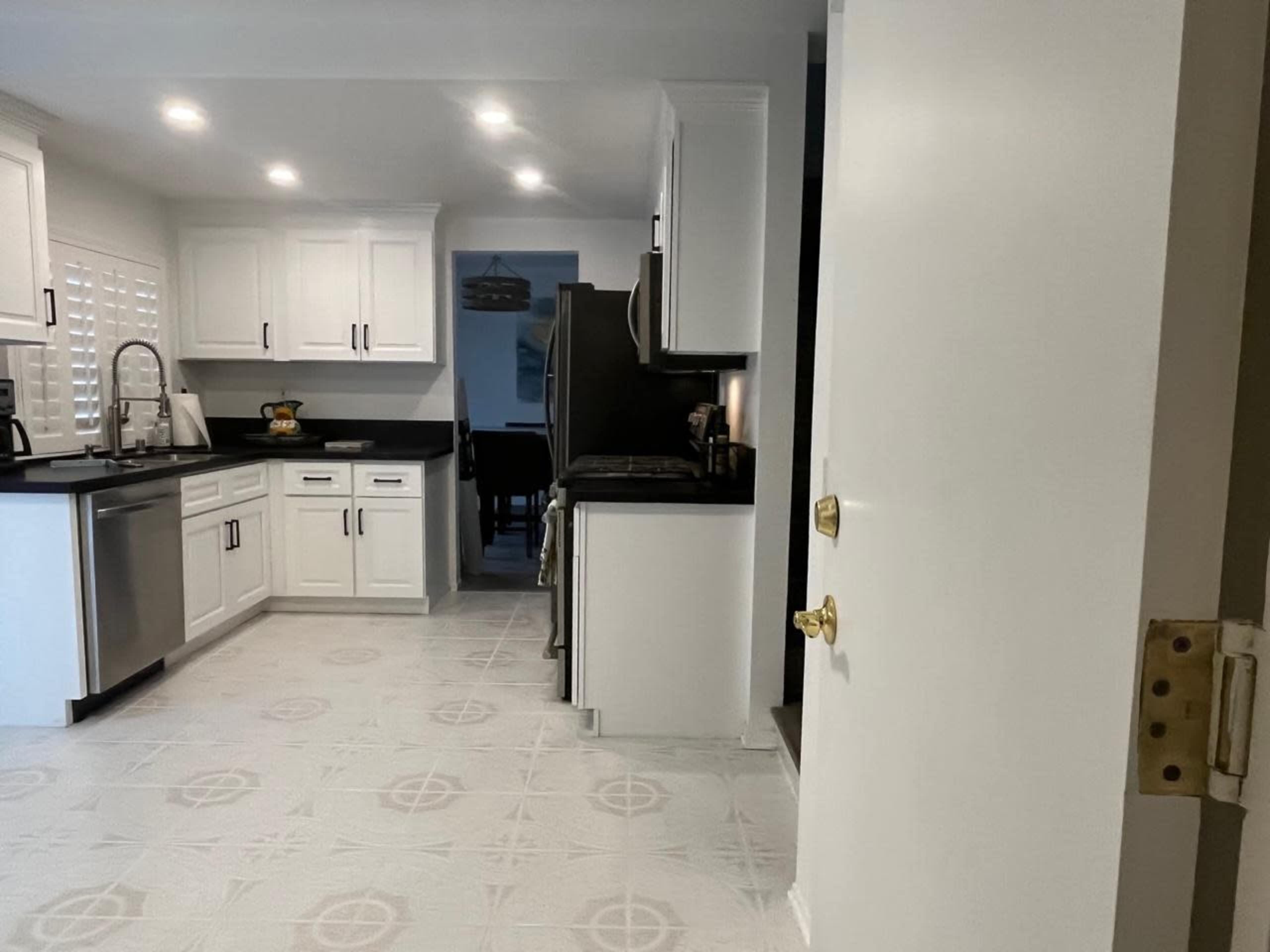 A modern kitchen with white cabinets, a dark countertop, and a tiled floor.