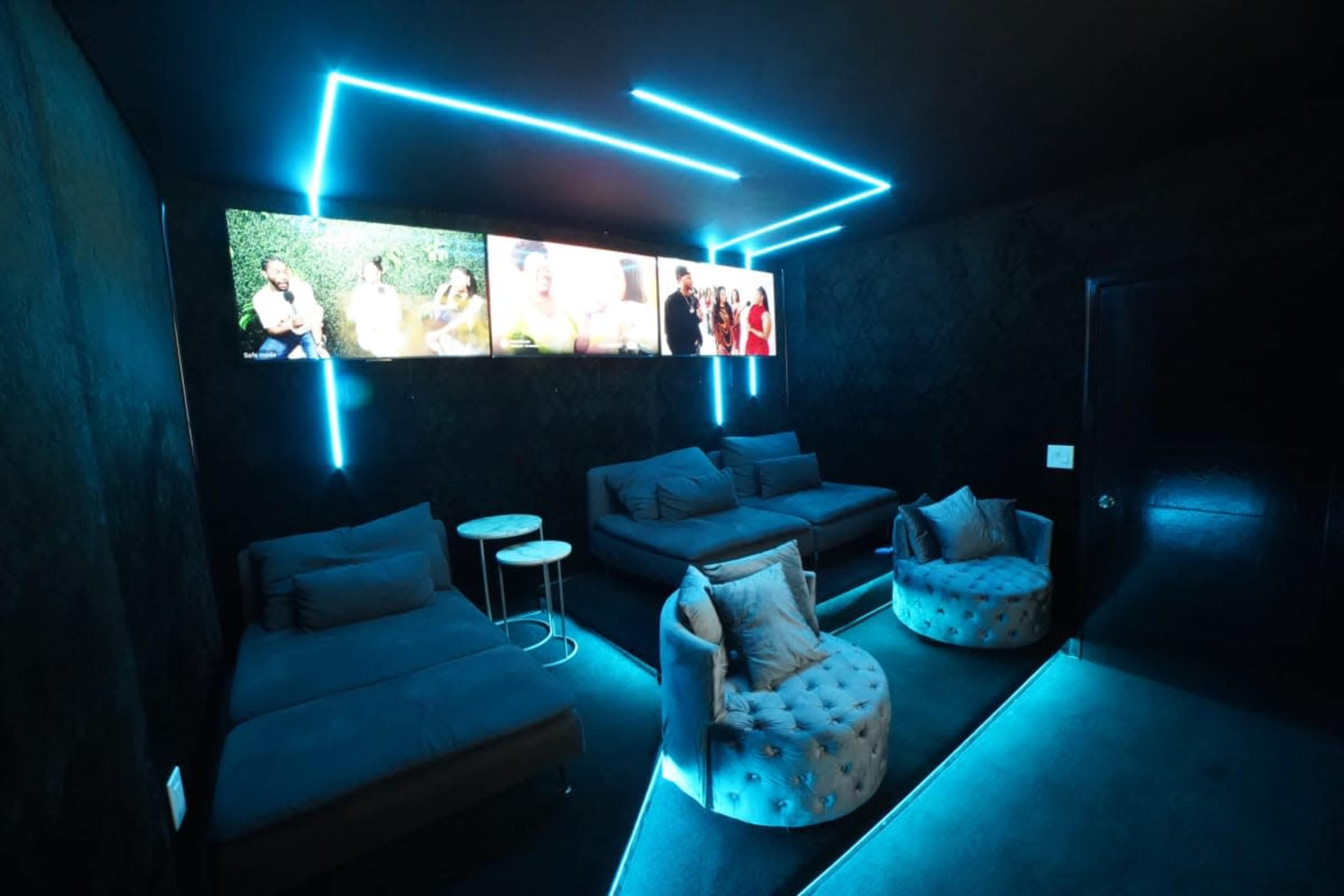 The room features modern seating arrangements with blue LED lighting and a wall-mounted screen displaying various images.