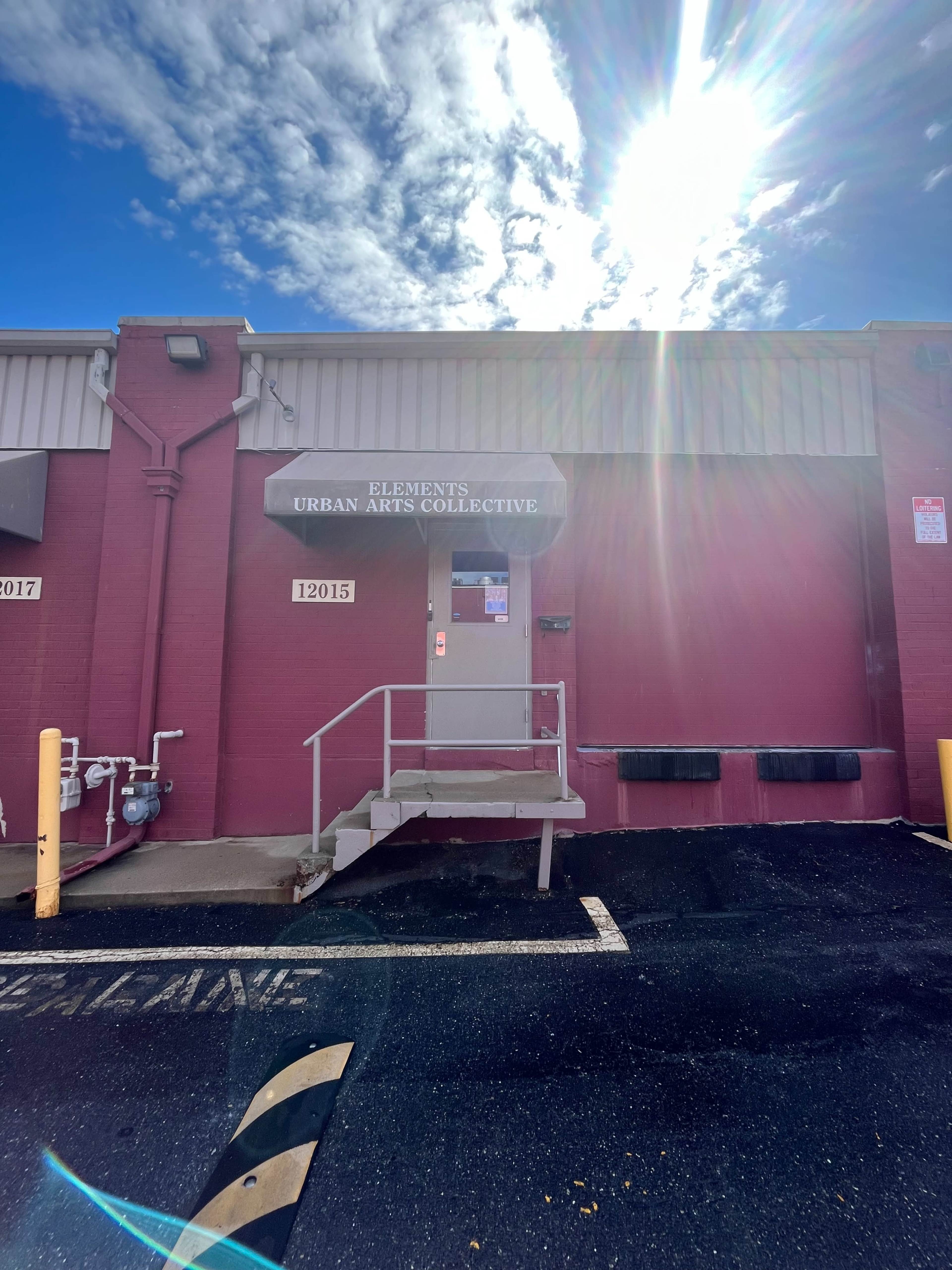 The entrance of a building labeled "Elements Urban Arts Collective," featuring a staircase and a canopy above the door.