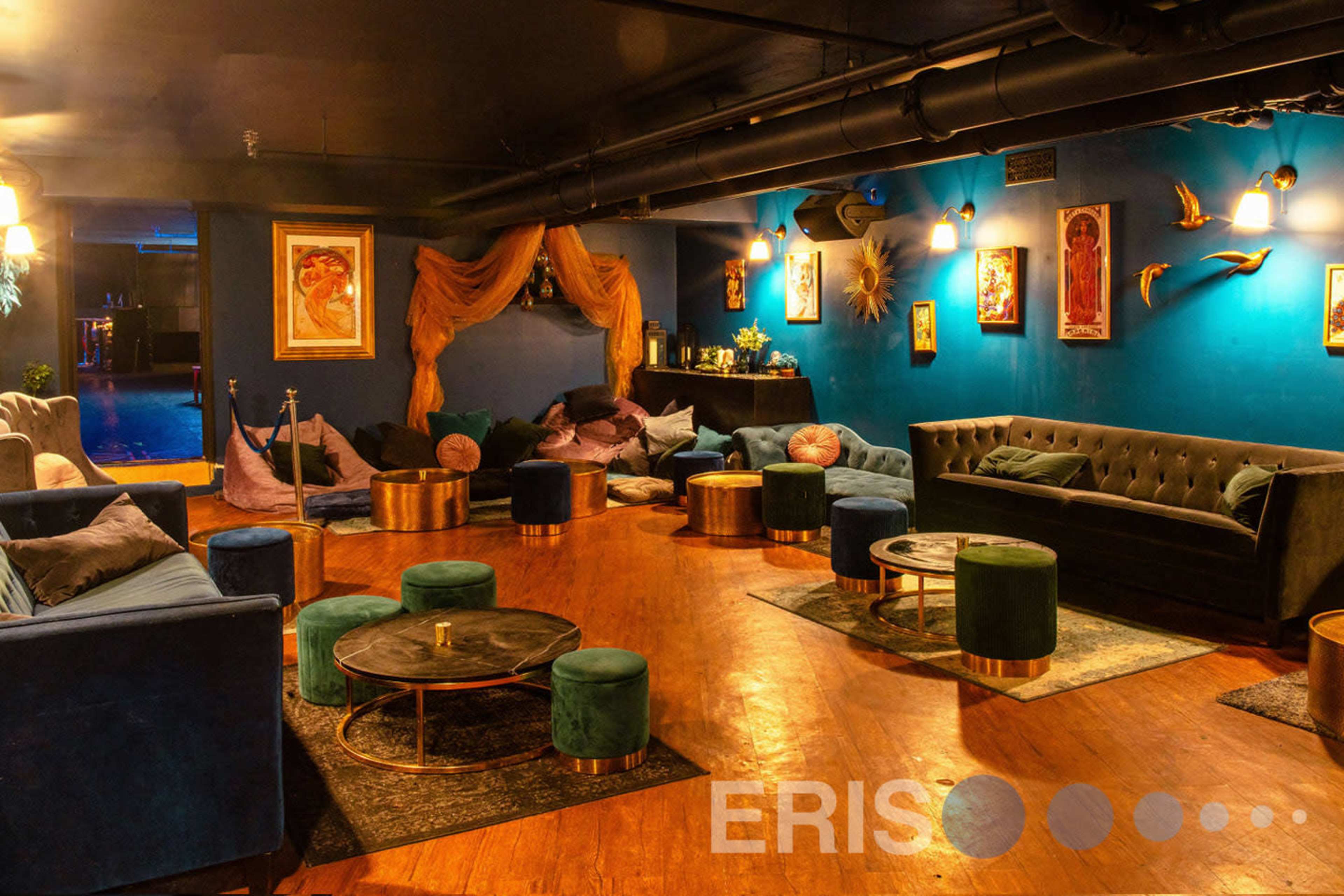 A cozy lounge area with velvet sofas, low tables, and art-filled walls.