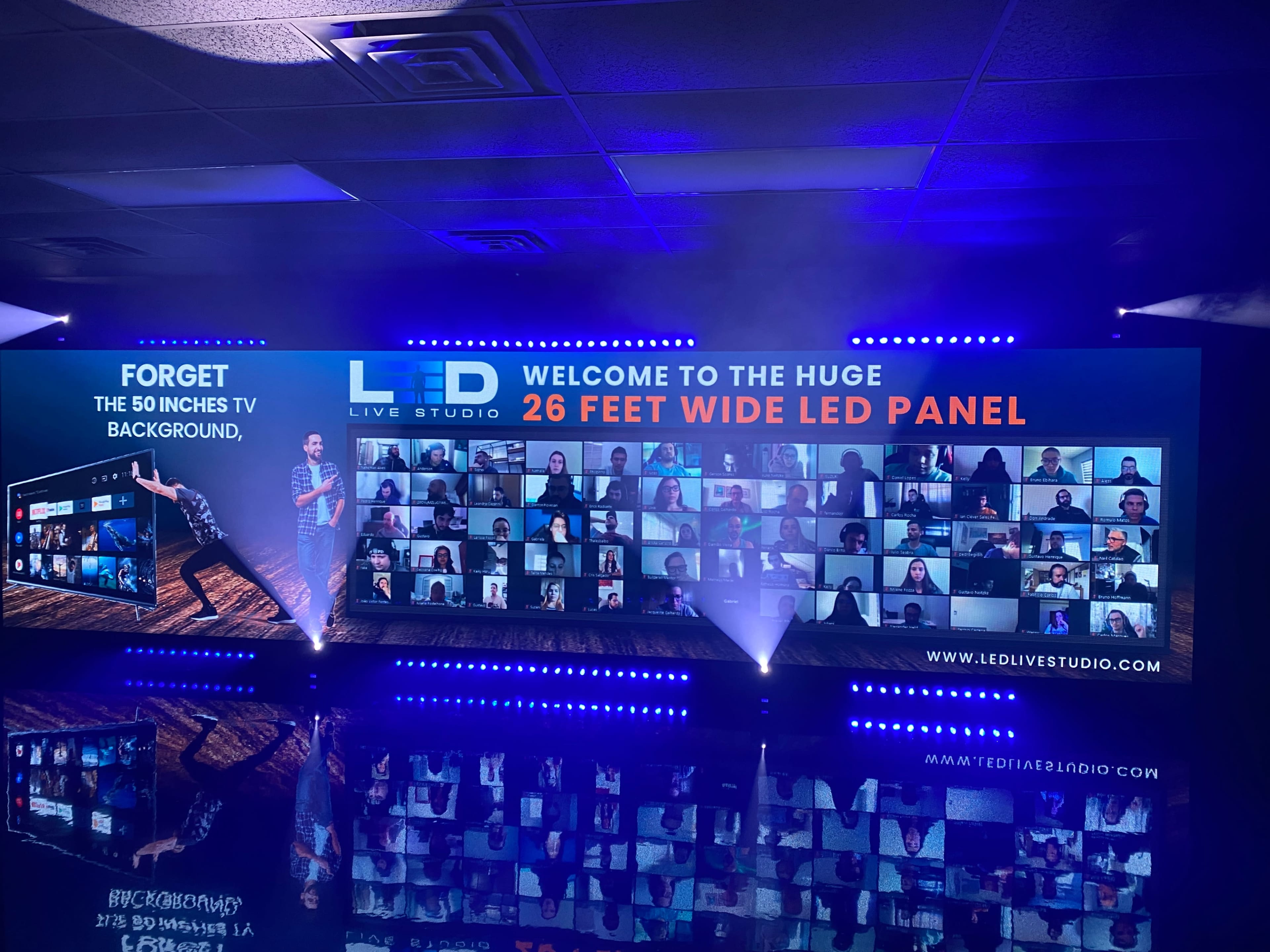 A promotional setup featuring a large LED panel displaying multiple video screens with people, alongside vibrant lighting and a banner that welcomes visitors to an LED live studio.