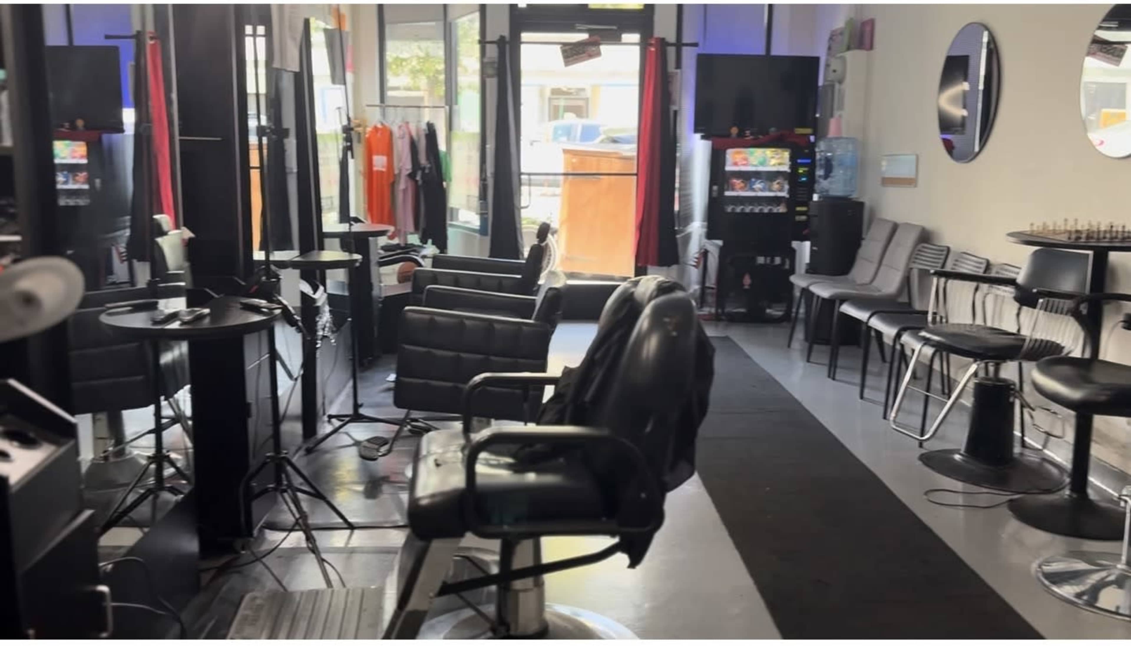 The image shows the interior of a barbershop with several styling chairs, mirrors, and seating for waiting customers.
