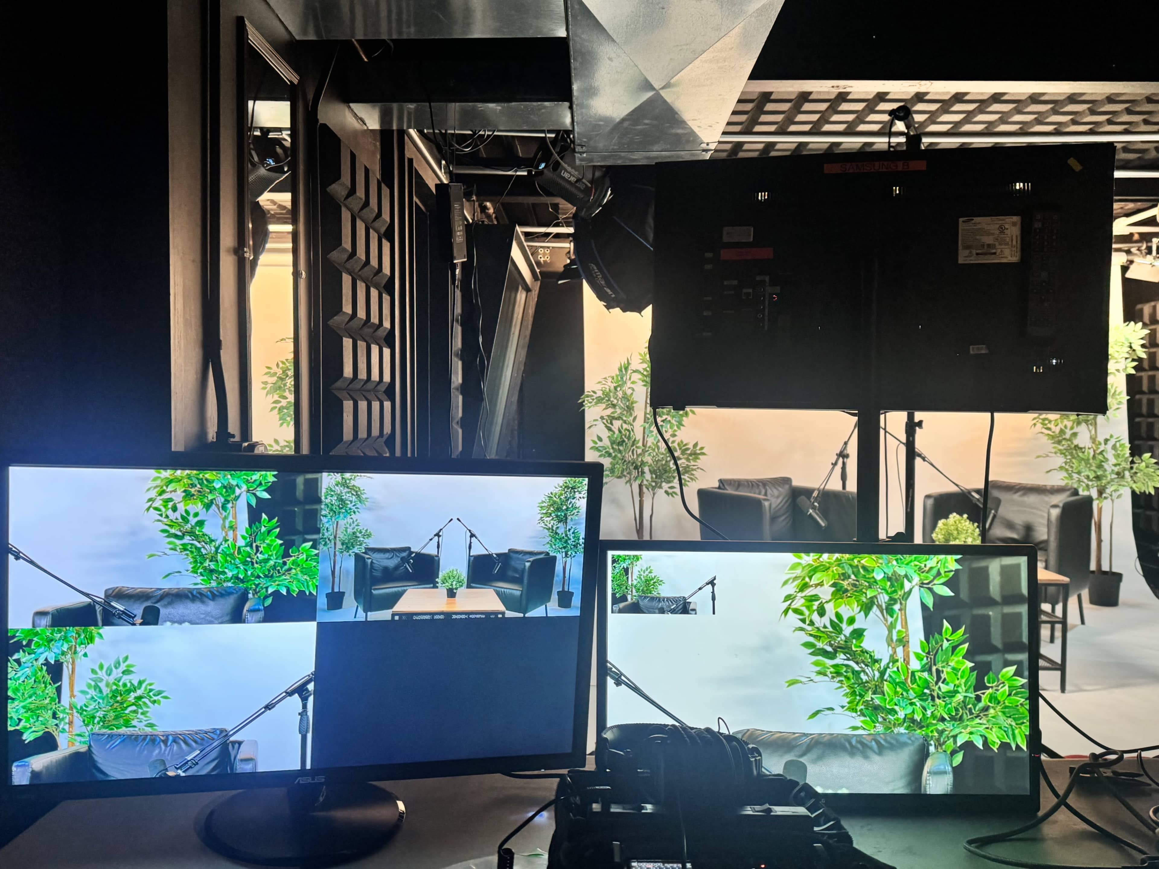 The image shows a setup with multiple computer monitors displaying different camera angles of a staged room featuring plants and seating.